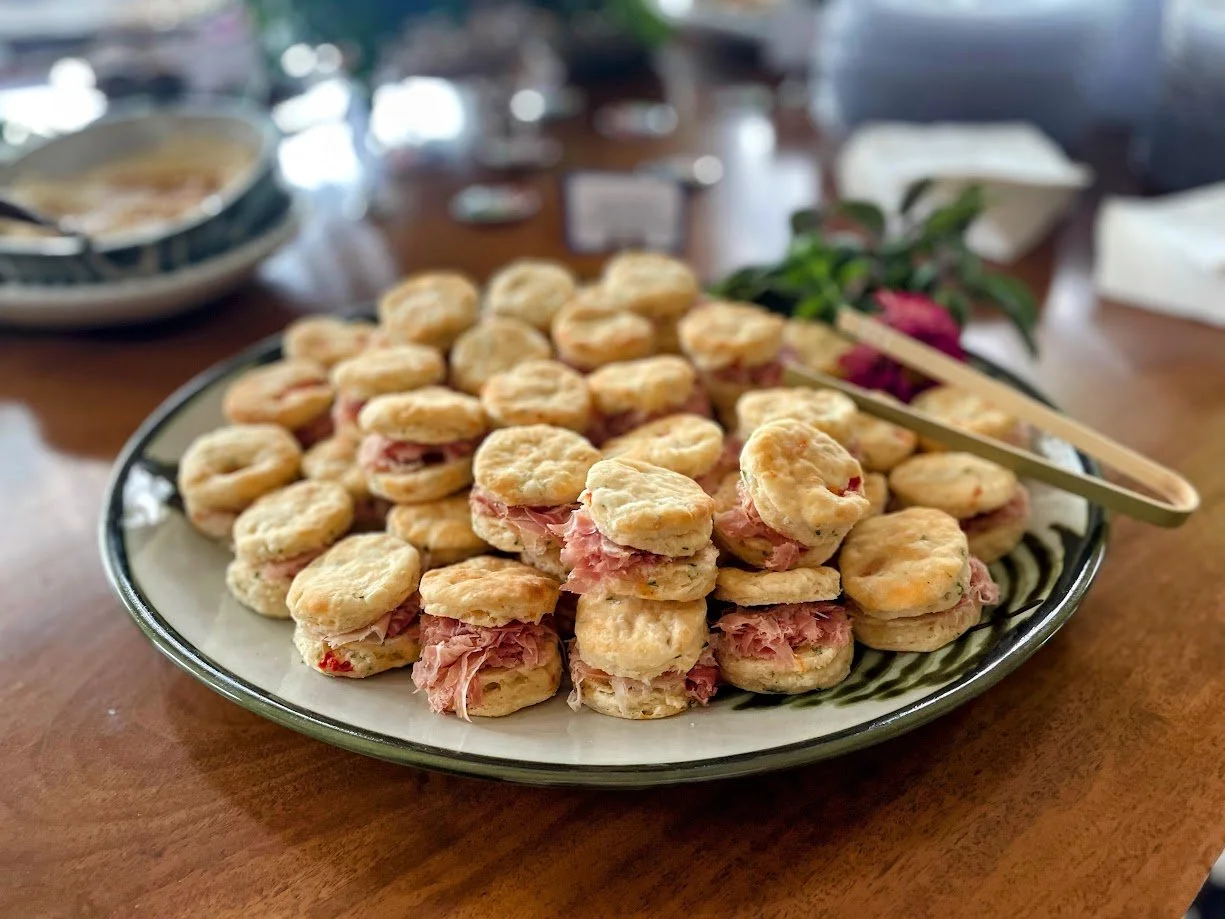 Plate of small sandwiches with ham and cheese on a table