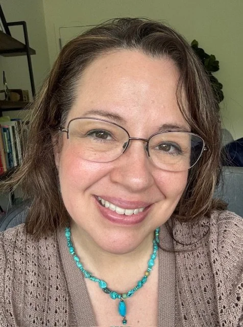 Irene Ilachinski with warm smile, brown eyes with glasses, brown hair