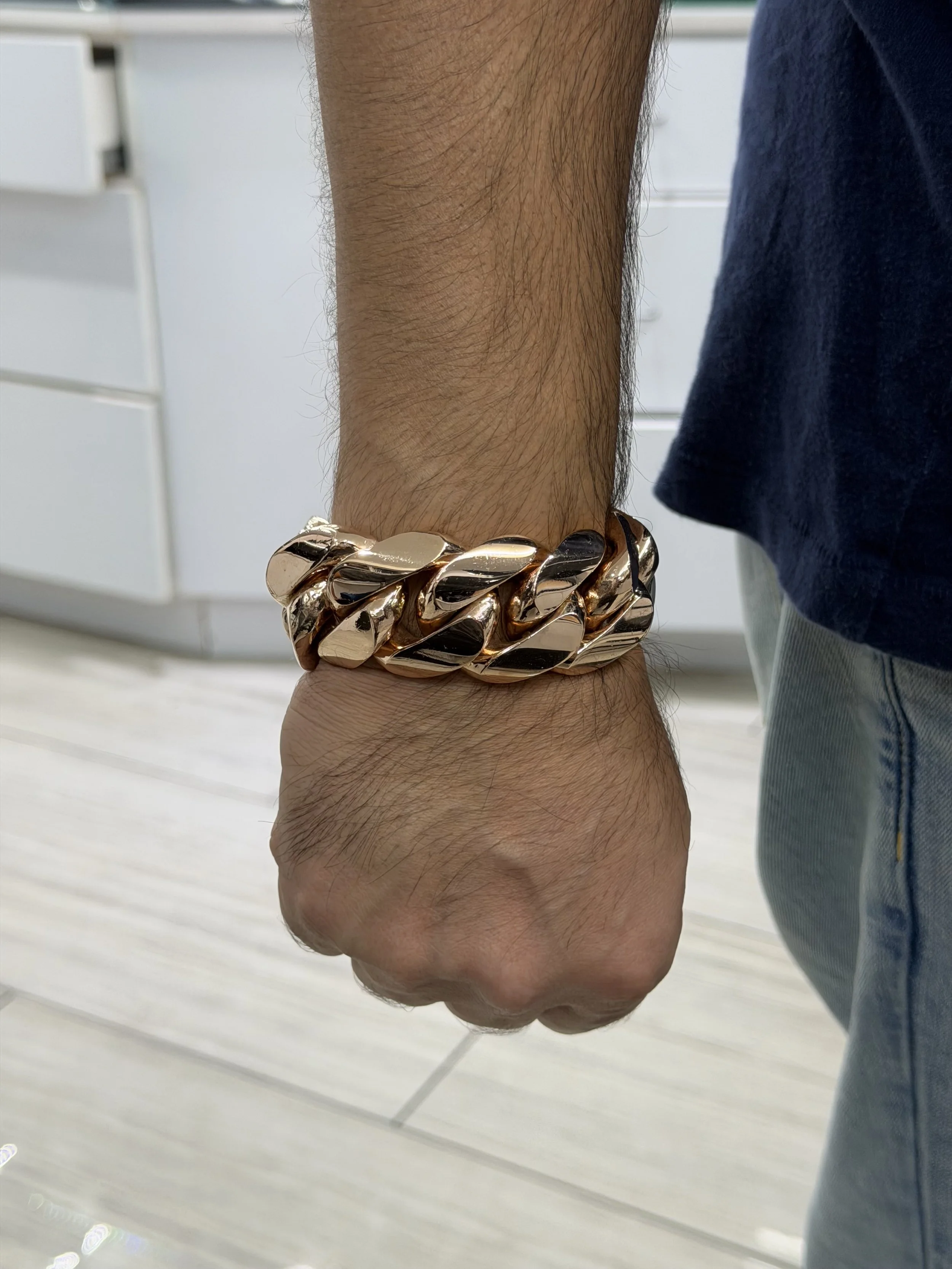 Solid 10KT rose gold Miami Cuban bracelet, 605.3 grams, 31.6mm wide and 9 inches long, shown on wrist at Gold N Diamonds Tampa