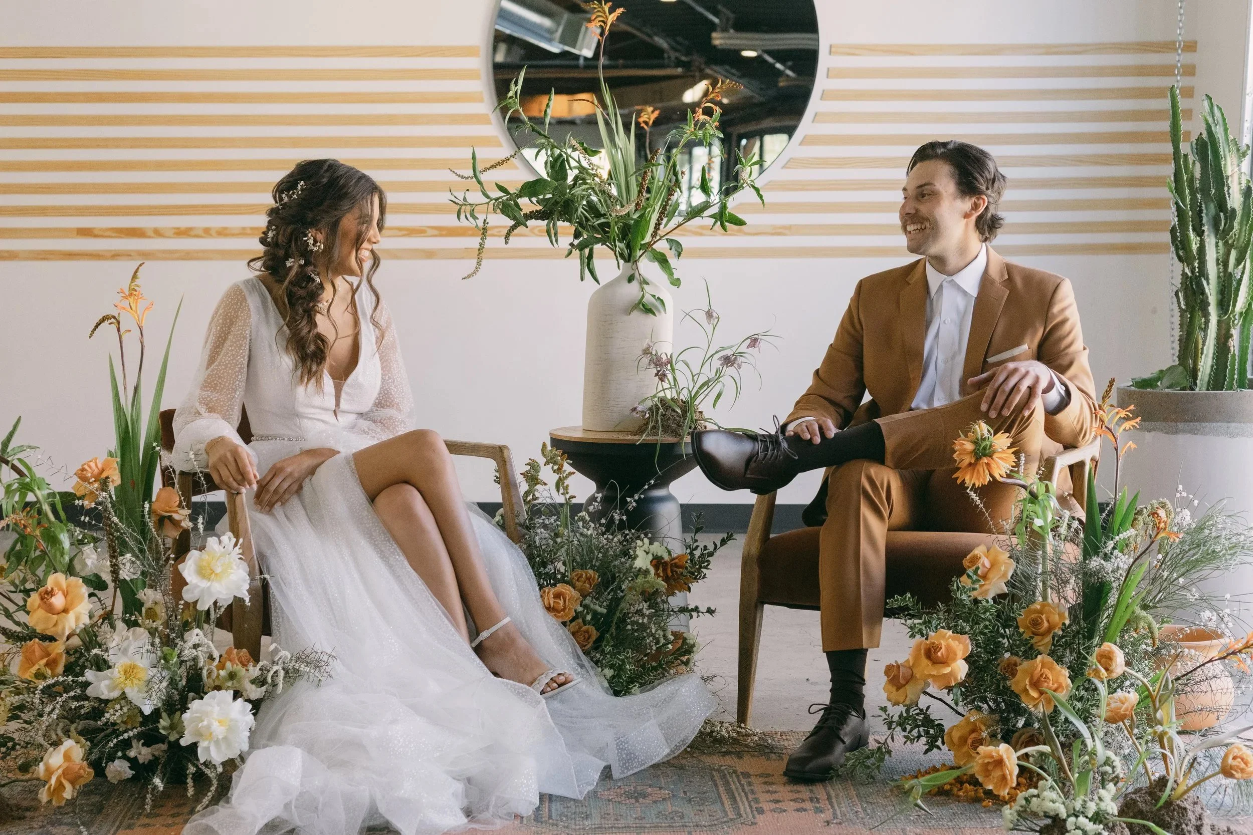 A happy couple after their ceremony, sitting in beautiful rental chairs and surrounded by flowers at their wedding