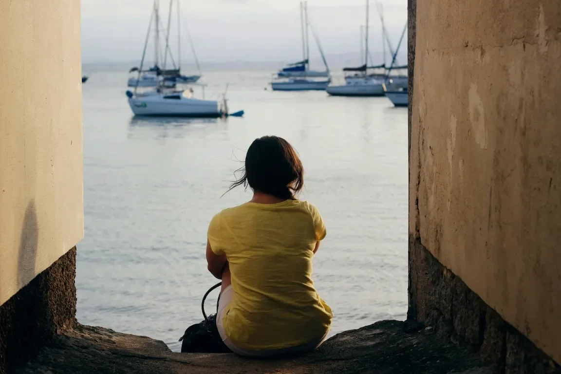 Woman sitting on perch overlooking a harbor