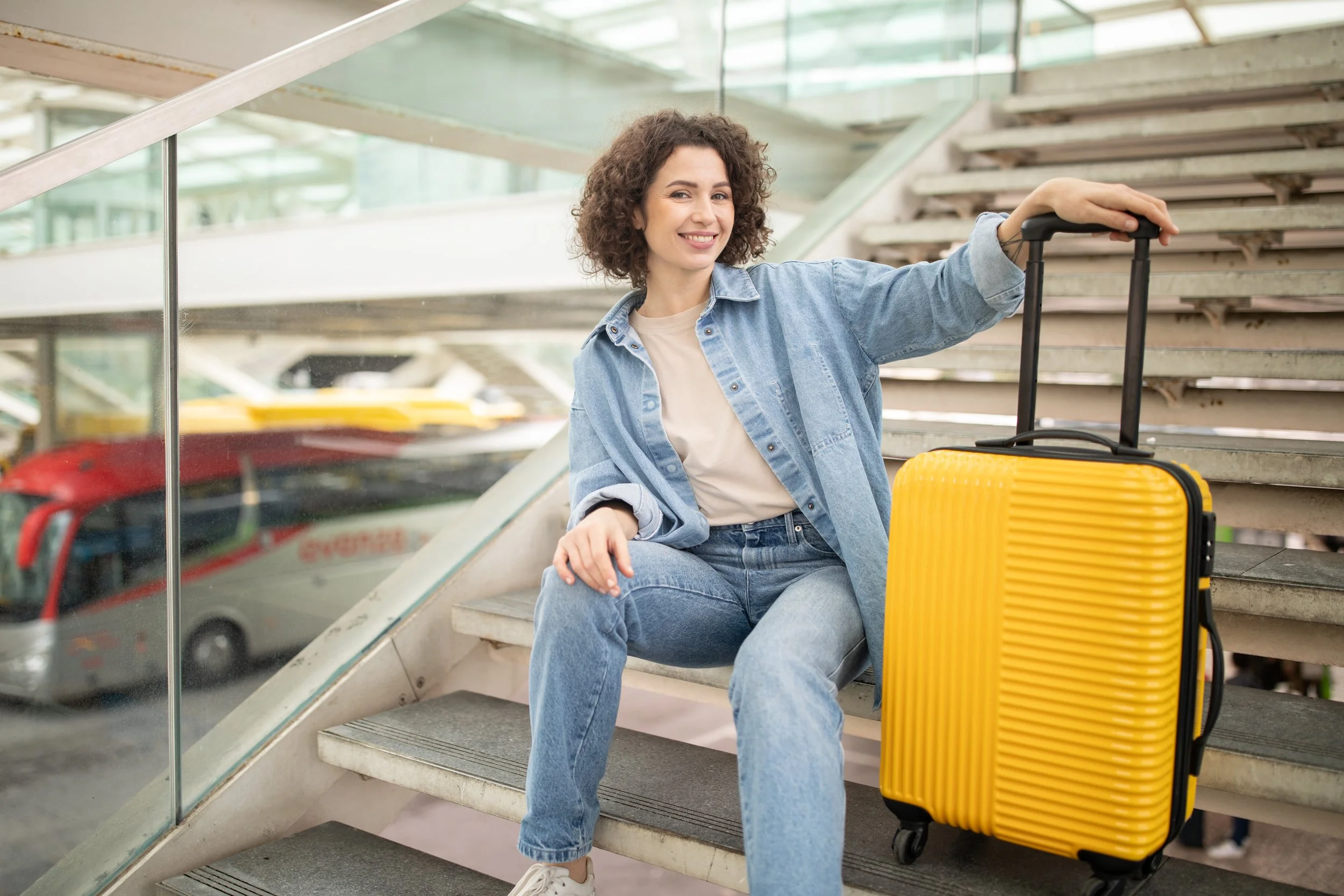 young-woman-sitting-on-stairs-with-yellow-suitcase-2025-03-18-19-27-22-utc.jpg