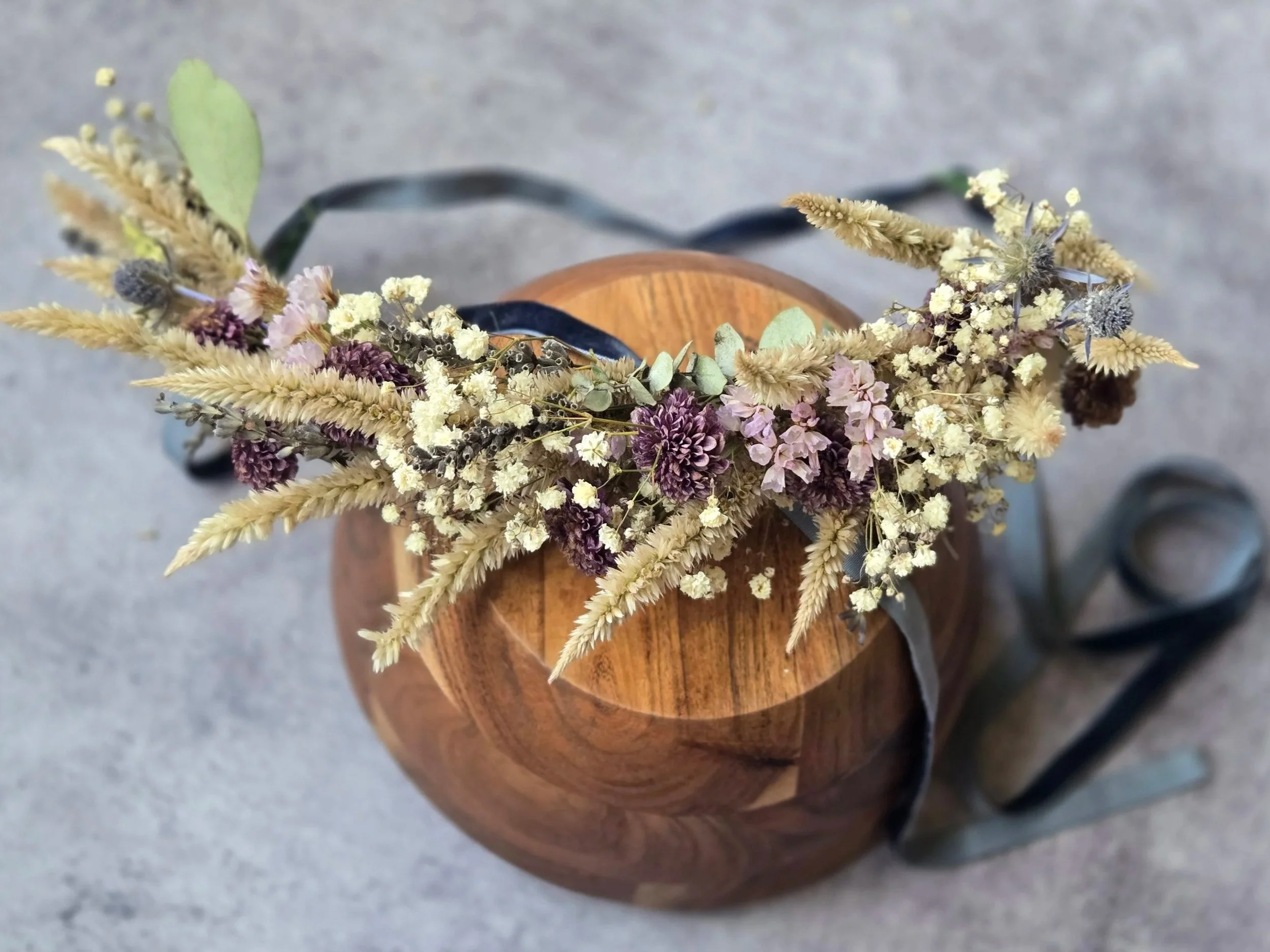 Flower arrangement on a table with vases of pink, yellow, and white flowers, and clear glass vases wrapped in plastic, set up outdoors on a white tablecloth.