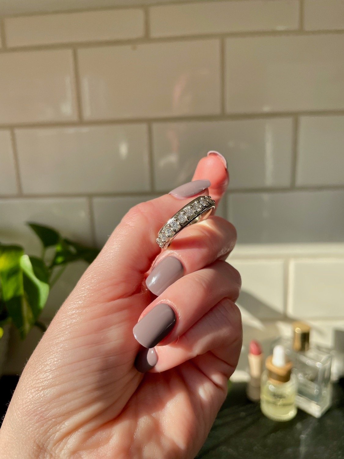 hand holding a white gold wedding band halfway covered in diamonds