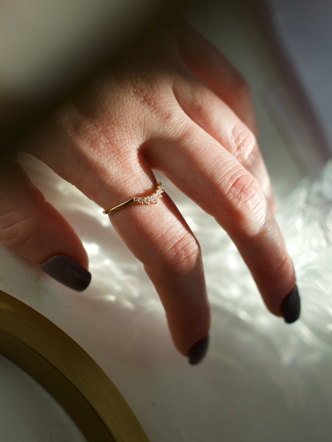 close up of a dainty curved diamond ring with seven small stones on hand