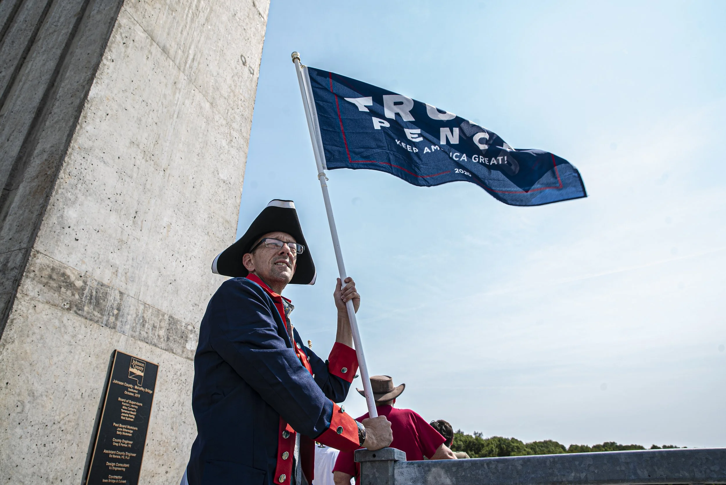  An anonymous Ottumwa, IA citizen waves a flag over a group of boats passing under a bridge over Coralville Lake on Monday, Sept. 7, 2020. The alias he gave reporters was “Jimmy Liberty”. For Labor Day, a group of local Trump supporters decided to dr
