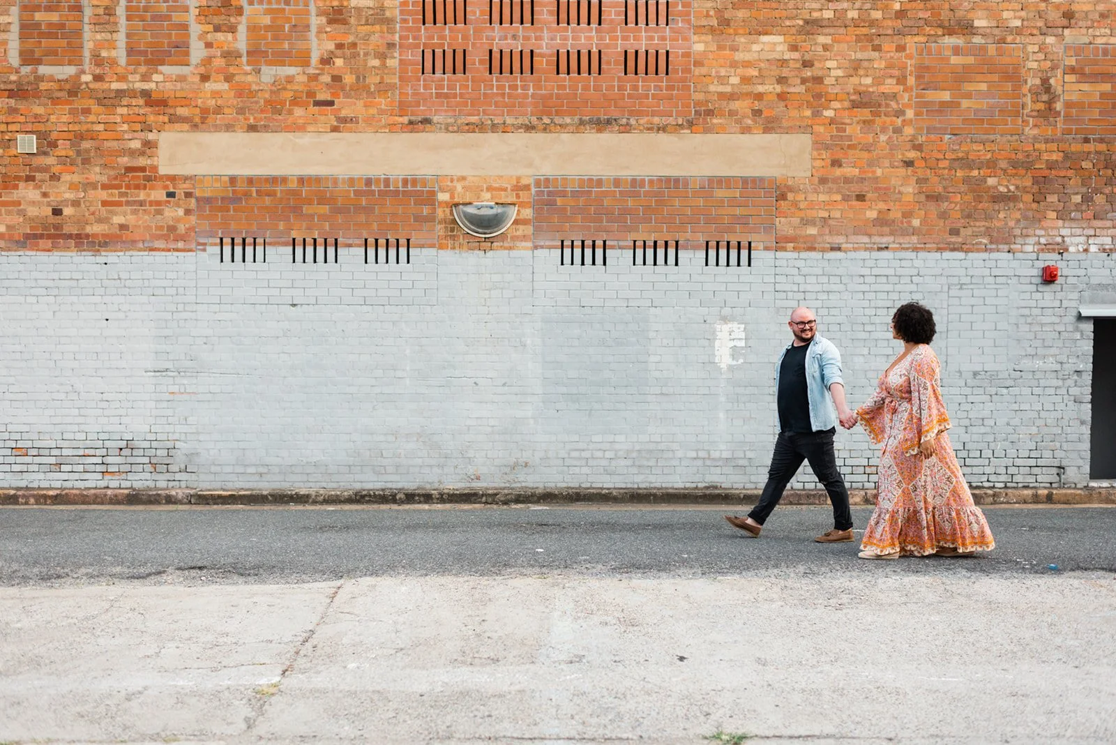 Couple walking hand in hand down a Fortitude Valley Laneway during their engagement session