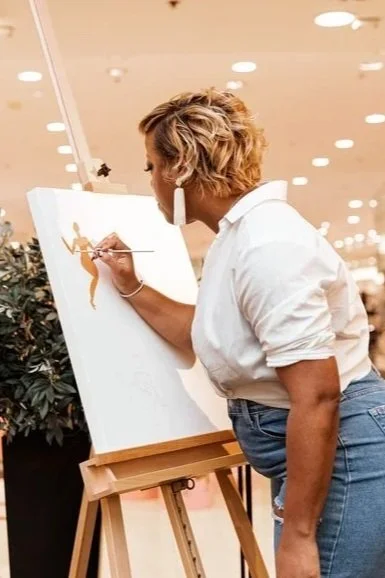 Melarie Odelusi painting artwork with earth tones on canvas at a Peloton in-store Black History Month brand activation. 