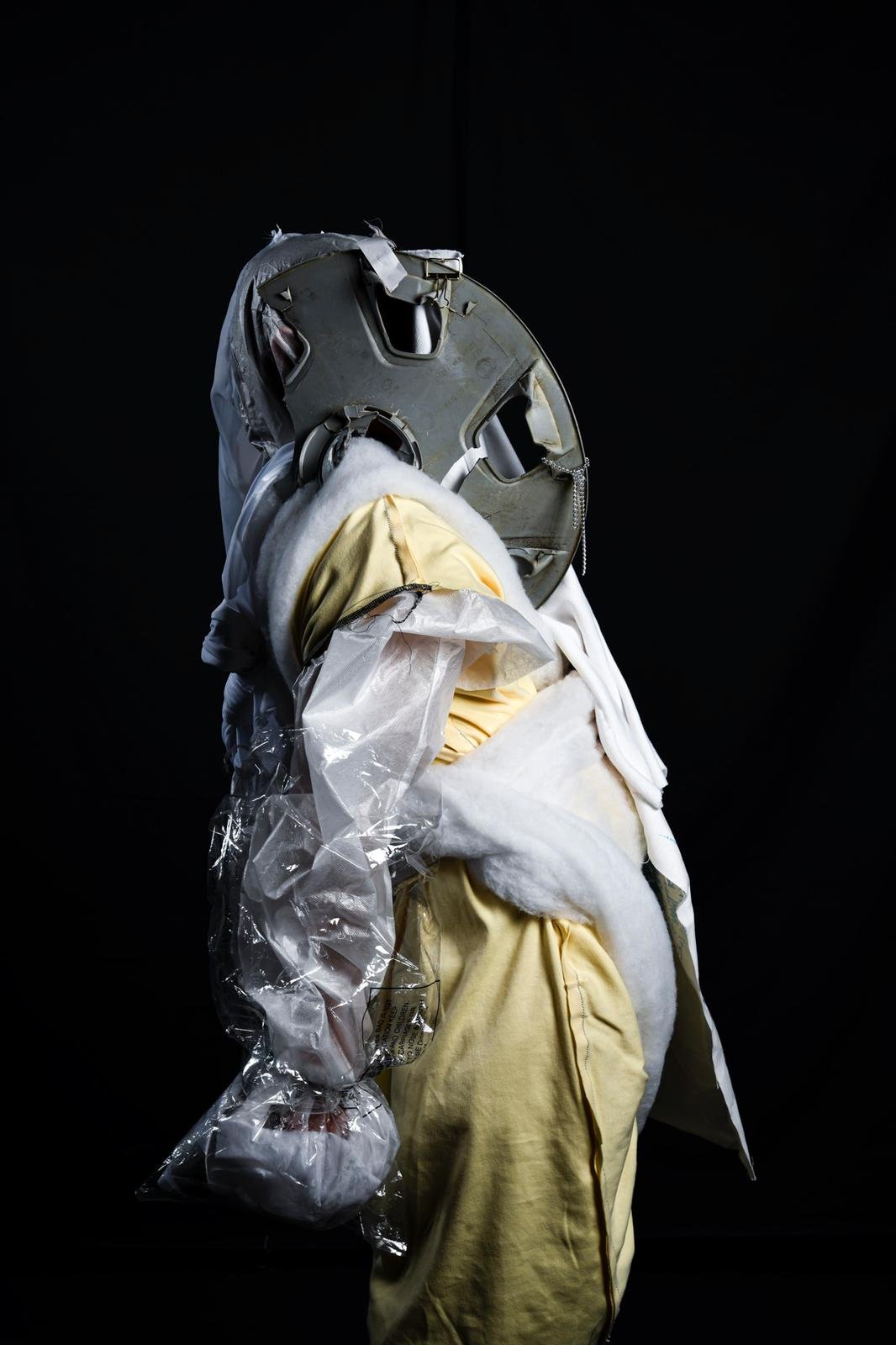 A display of astronaut gear, including a helmet, gloves, and protective clothing, against a black background.
