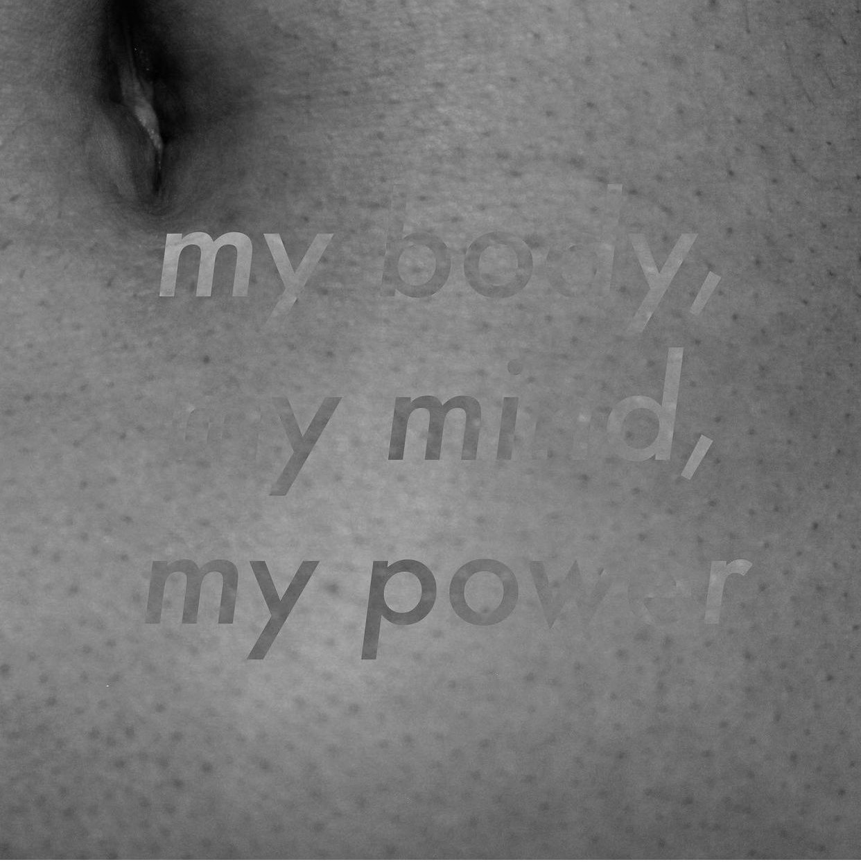 Close-up of a textured surface with faint, blurry words engraved, including "my body," "my m," and "my p" in a small, italic font.