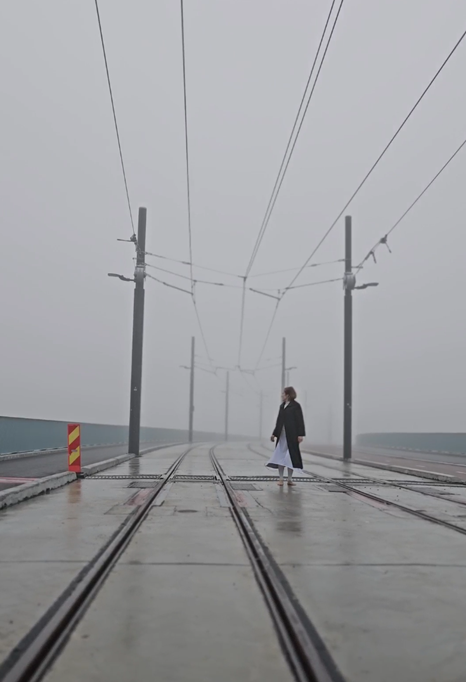 person walking on the tram tracks in a foggy landscape