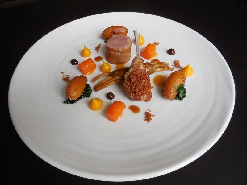 Agneau de lait de l’Aveyron Cote et selle rôties saupoudrées de pralin d’ail, déclinaison de carottes, jus parfumé au foin