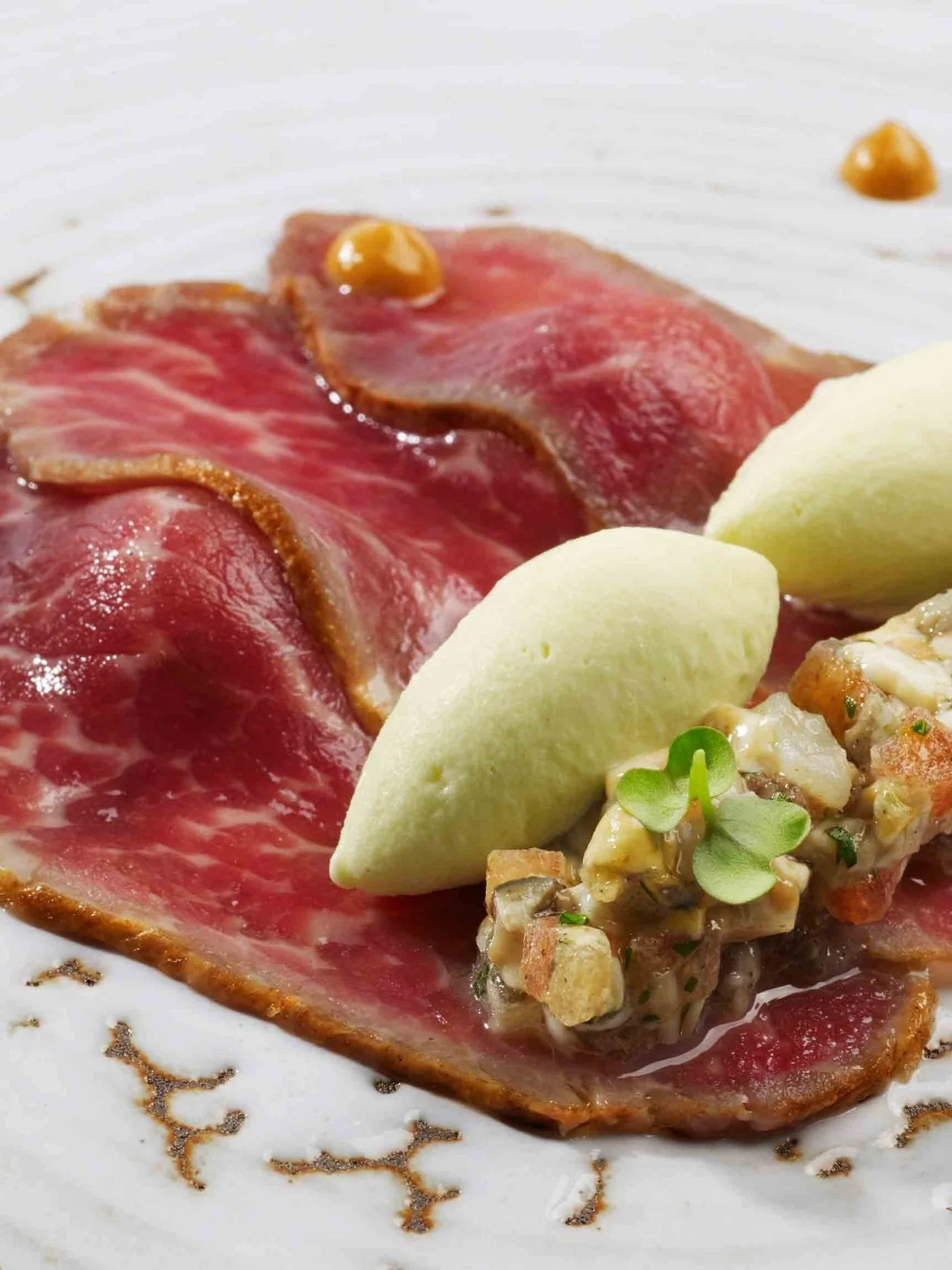 Láminas de presa ibérica atemperada sobre cuajada de foie gras, tarama de ostras y helado de mostaza