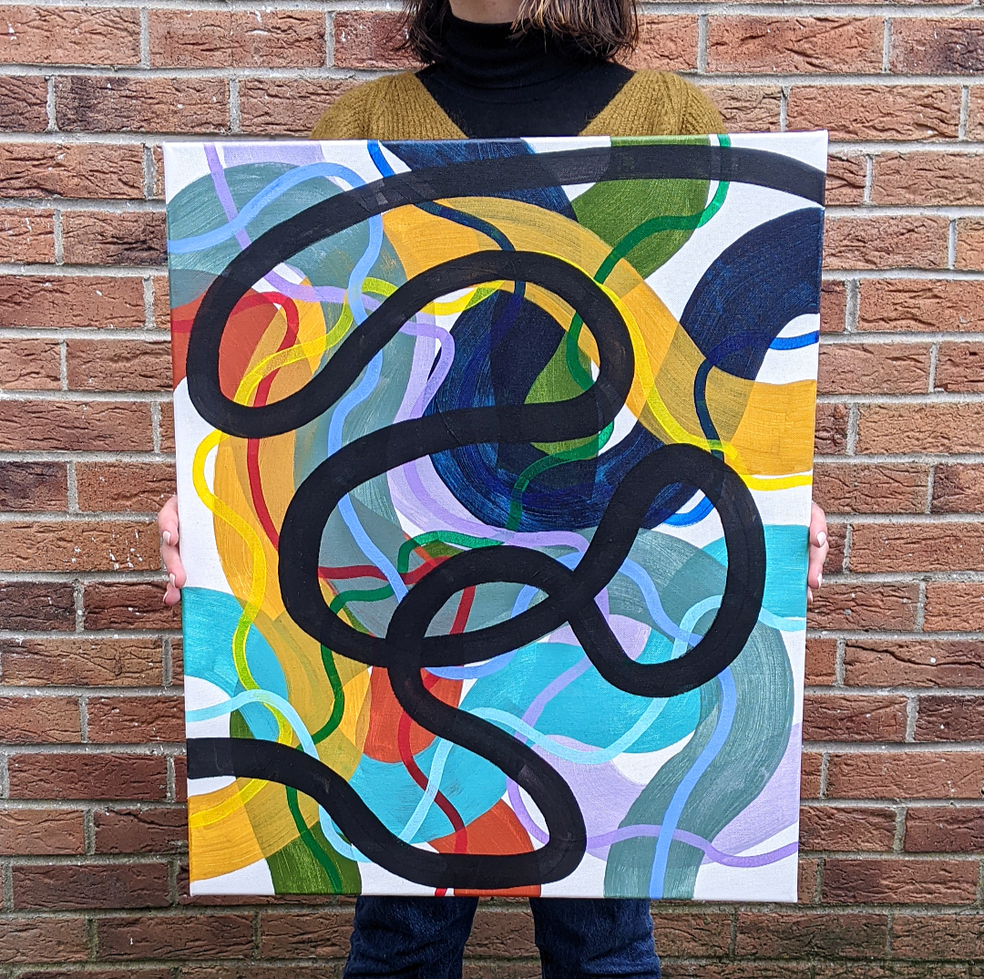 Abstract painting with colorful swirls and a bold black line held by a person against a brick wall.