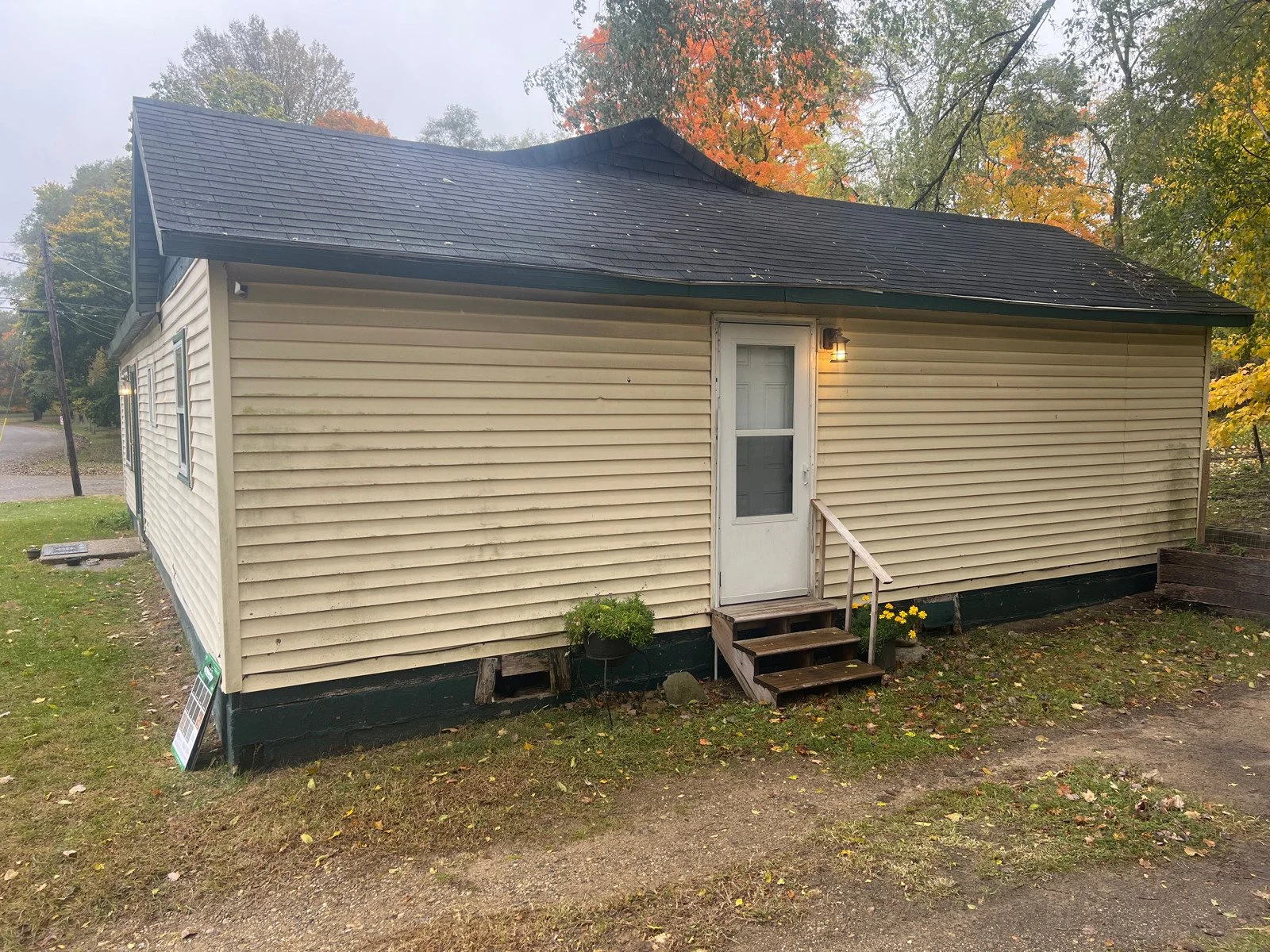 A small house with sagging roof line and worn siding.
