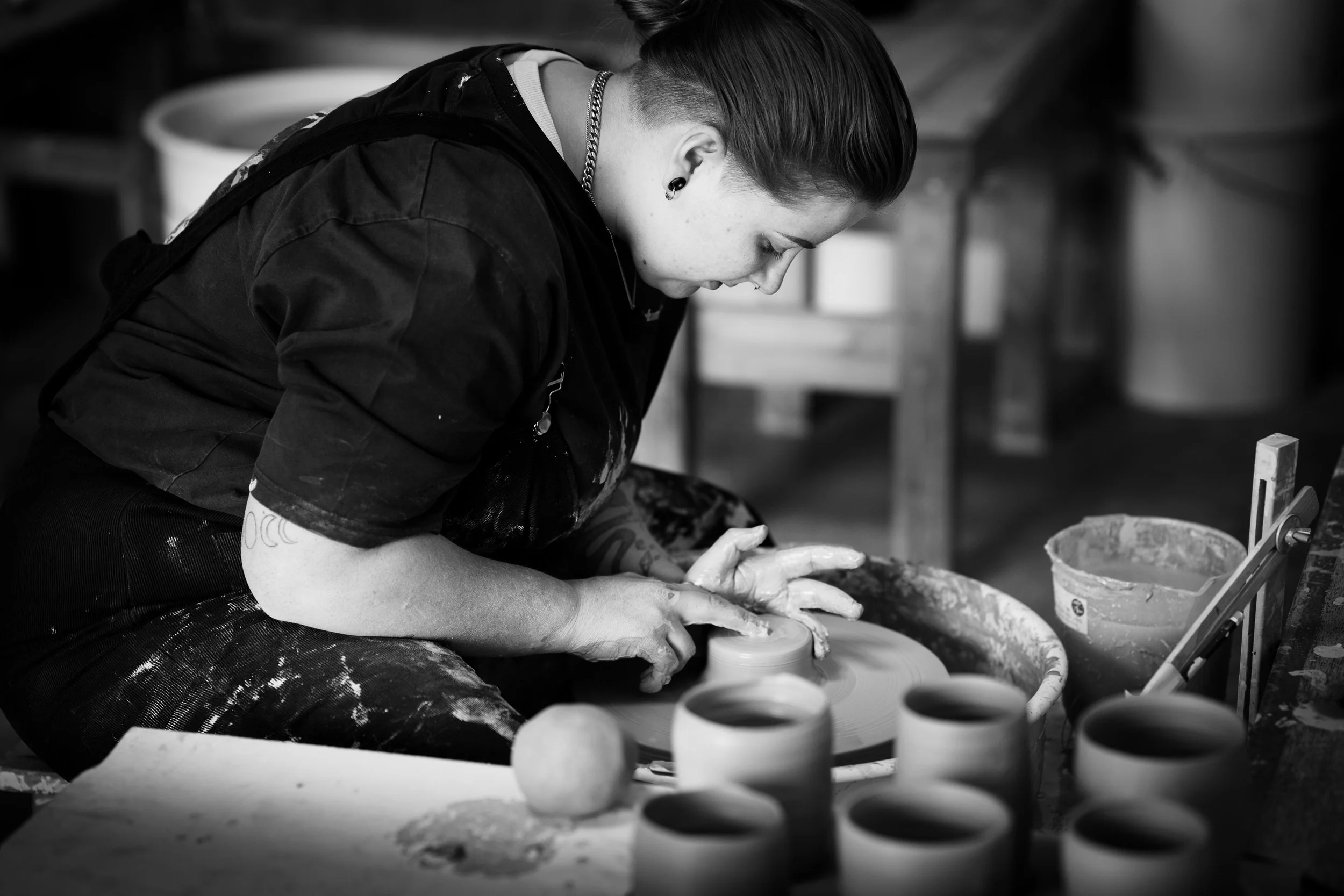A woman working on a pottery wheel shaping clay in a pottery studio at Wrexham University