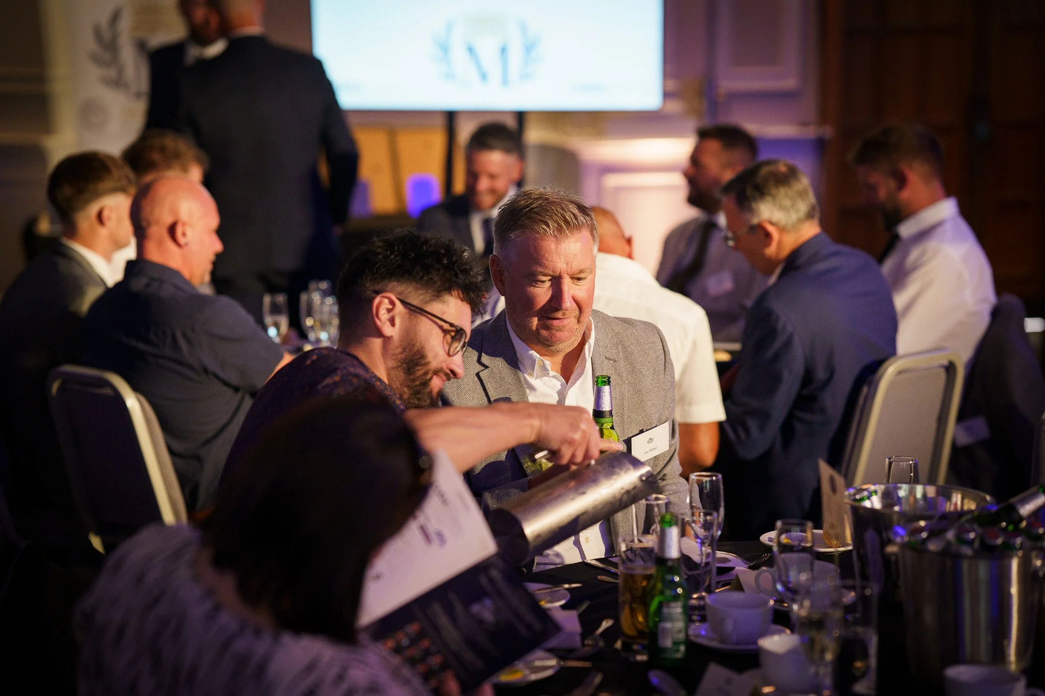 Candid photo of Group of men in formal attire sitting at a banquet table at awards event in Chester, Cheshire