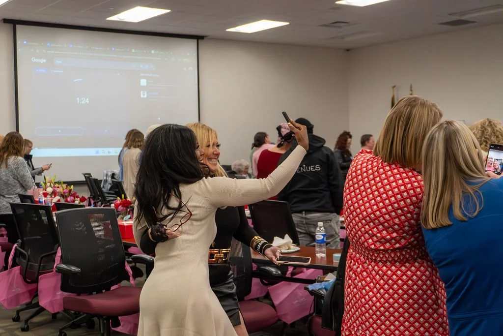 People in a conference room taking photos and socializing before or after an event.