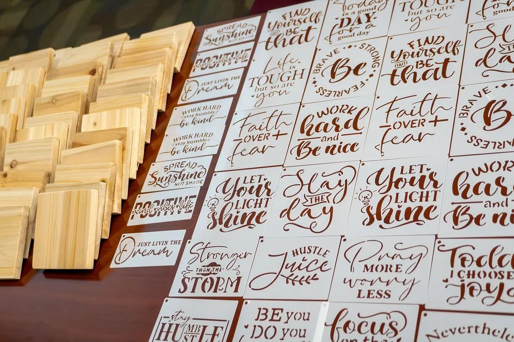 A collection of wooden stamps and sheets of printed quotes with motivational and inspirational phrases, arranged on a table.
