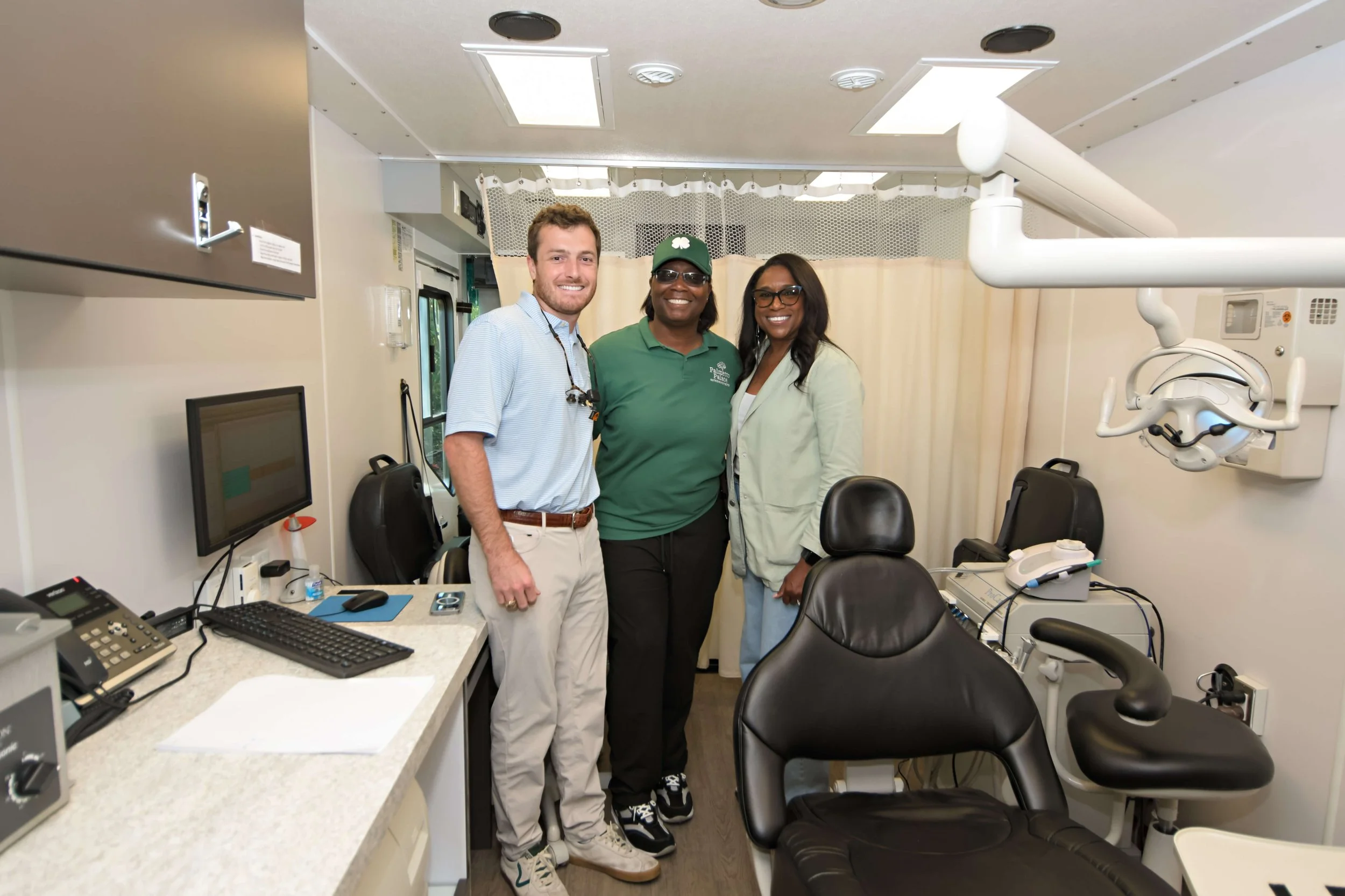 Three people smile in the mobile dental unit in SC