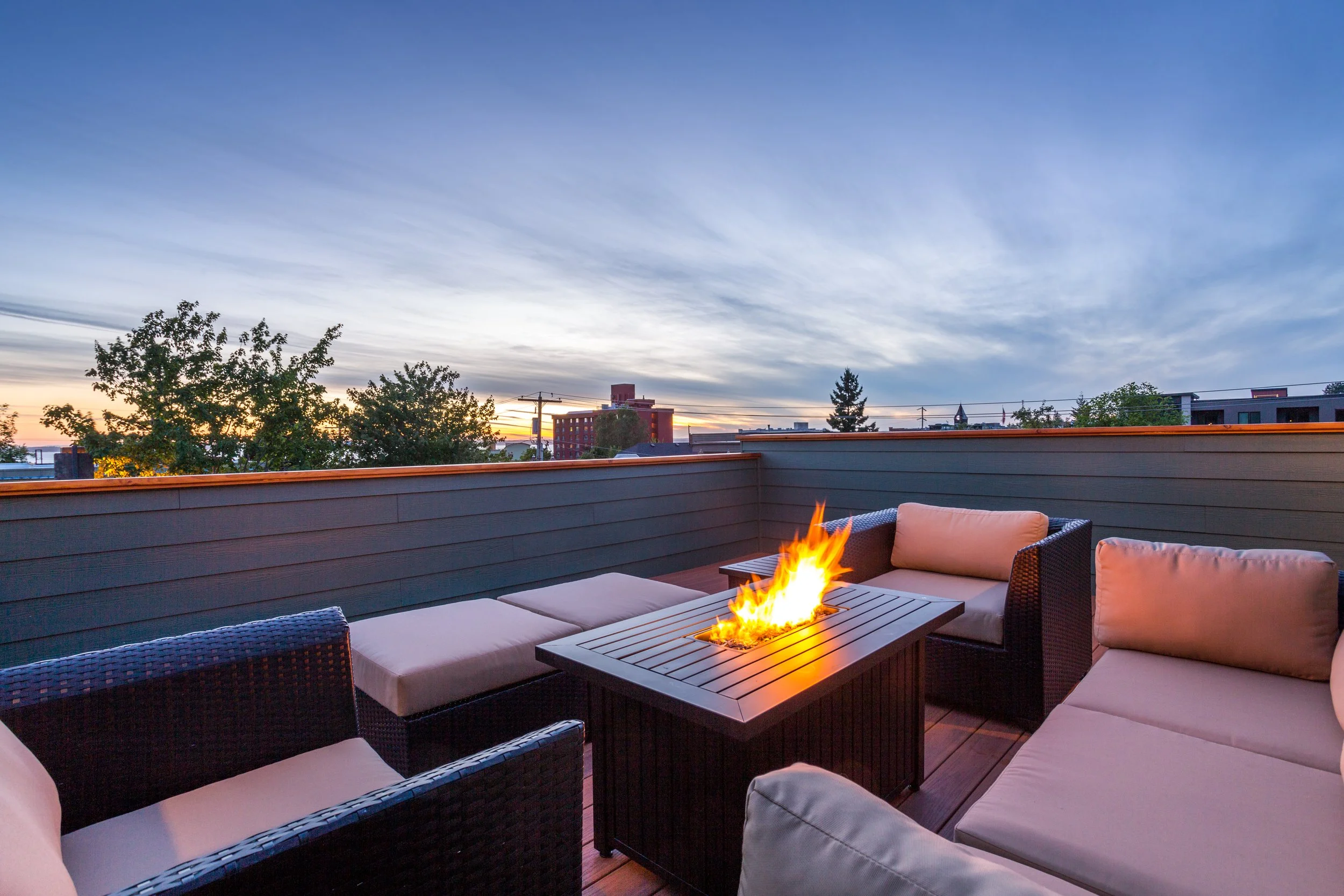 Rooftop patio at sunset with outdoor seating and a fire pit.