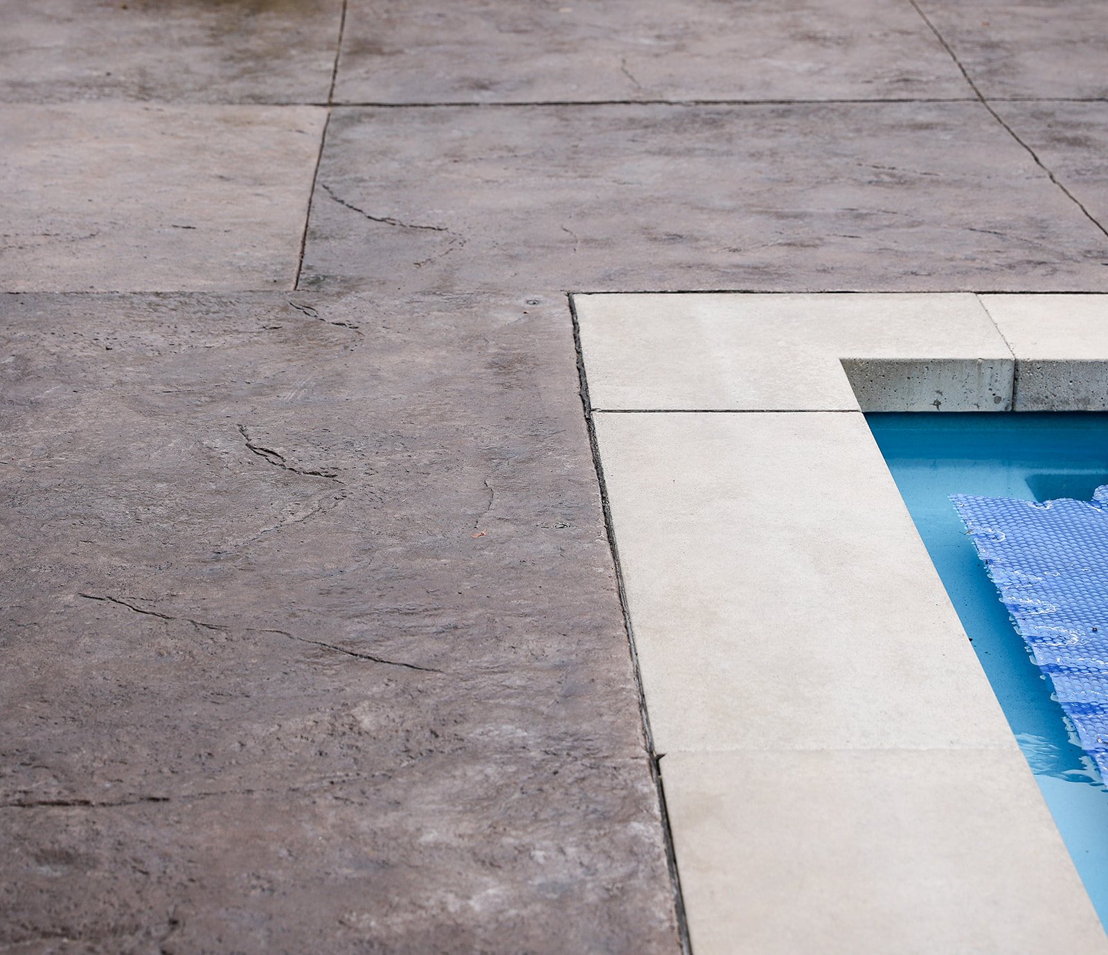 Pool edge with stone tiles and blue water surface