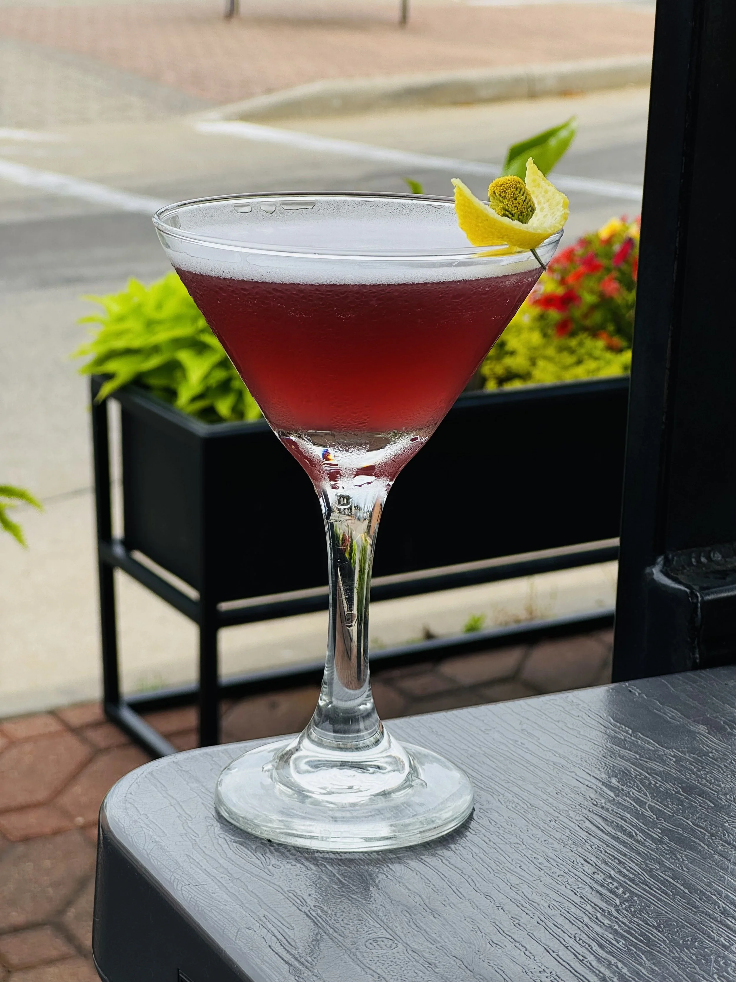 The Empress: 
Indigo Empress gin, blackberry liqueur, triple sec, fresh lemon juice, simple syrup fee foam garnished with a buzz button and lemon peel
