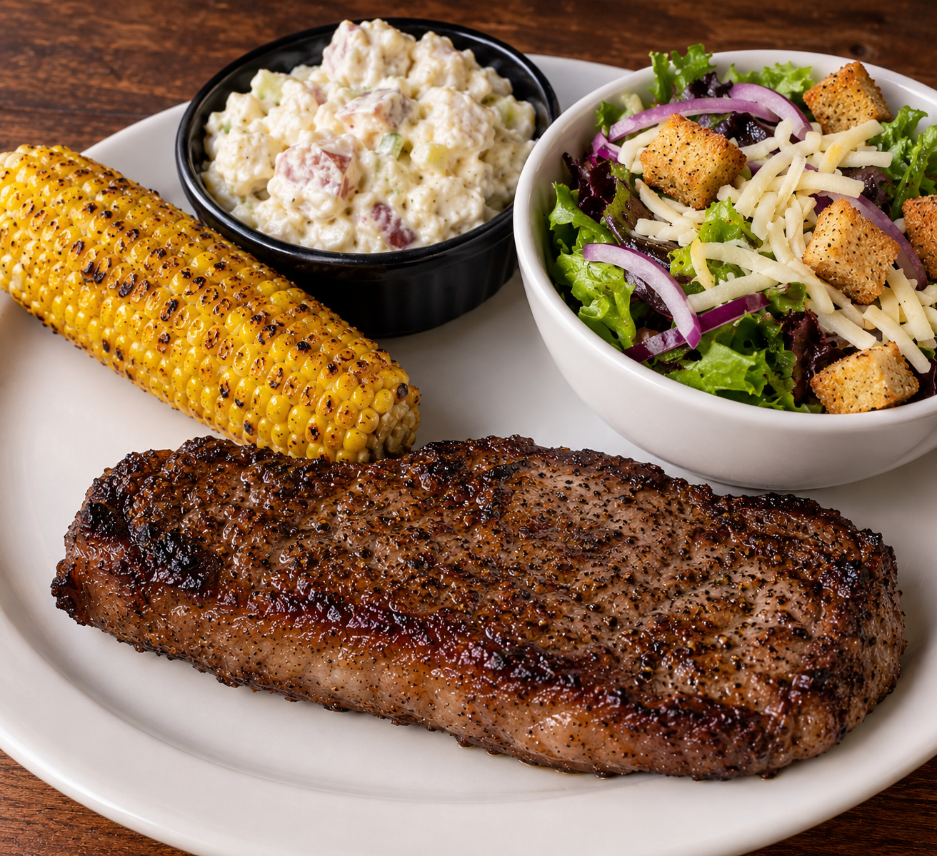 new york strip with potato salad and fried corn and a 1/2 house salad