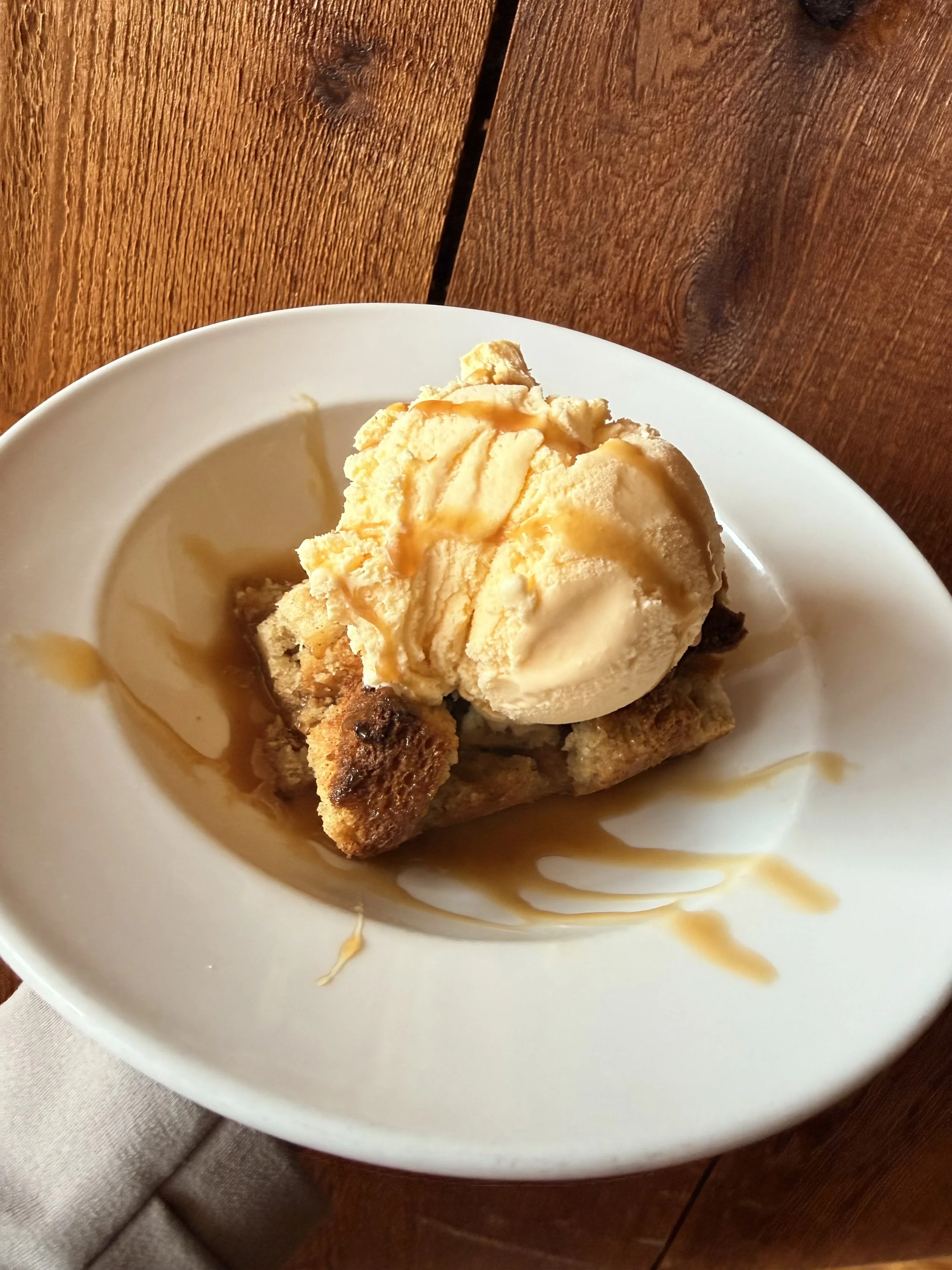Bread Pudding served with a scoop of vanilla ice cream and a caramel drizzle