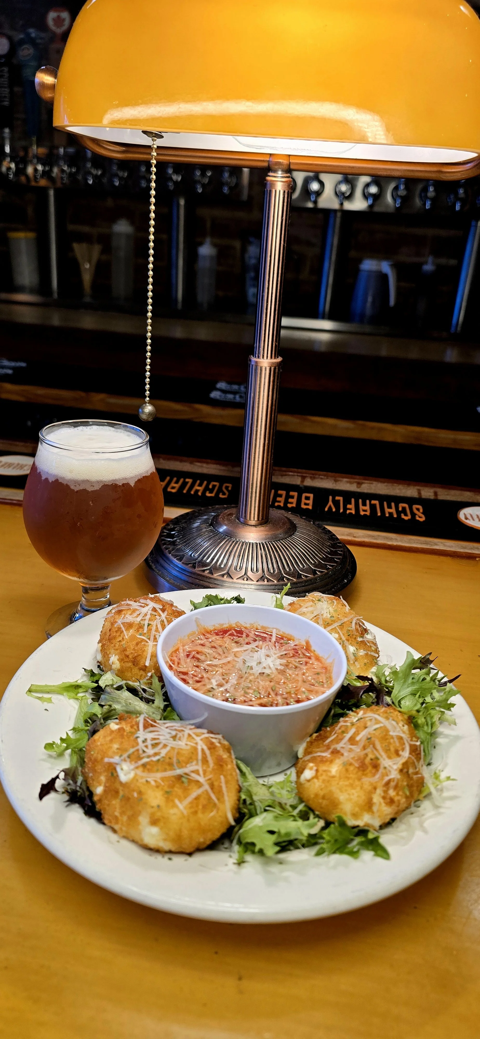 Panko fried Burrata balls on a bed of mixed greens served with red sauce topped with parsley and fresh grated parm.