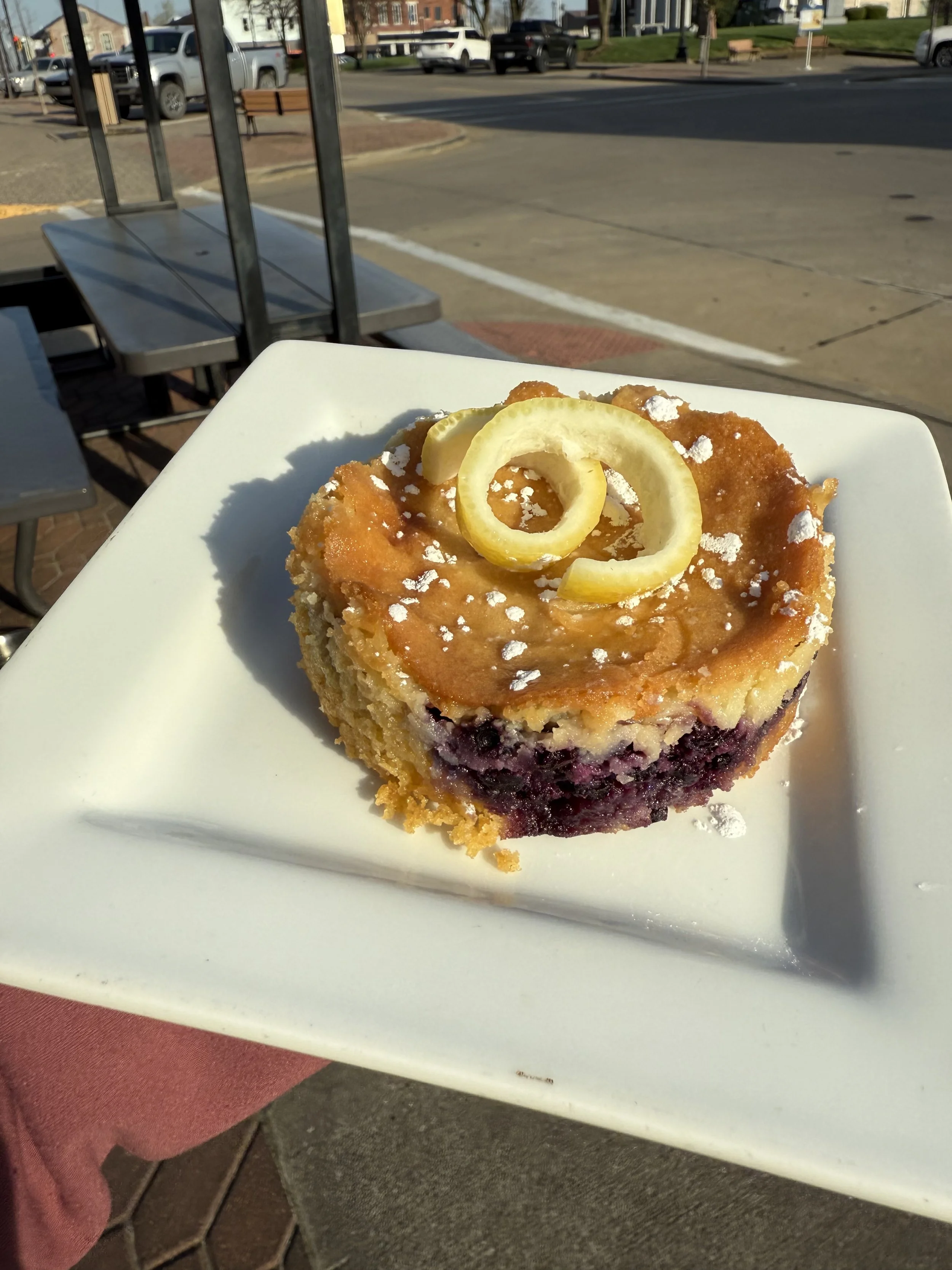 Blueberry lemon gooey  butter cake topped with powdered sugar and a lemon twist