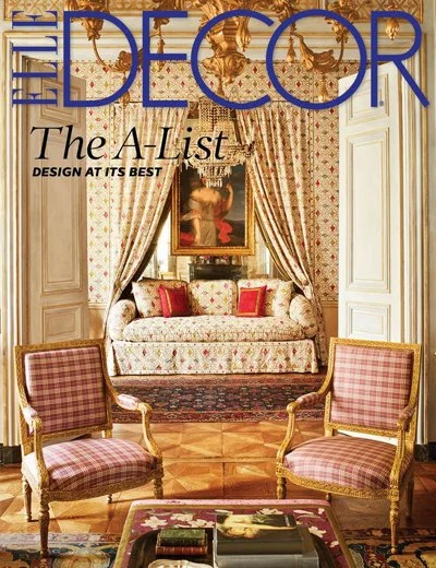 Cover of Elle Decor magazine featuring an elegant living room with floral curtains, a classic sofa with red cushions, two armchairs with plaid upholstery, and a chandelier.