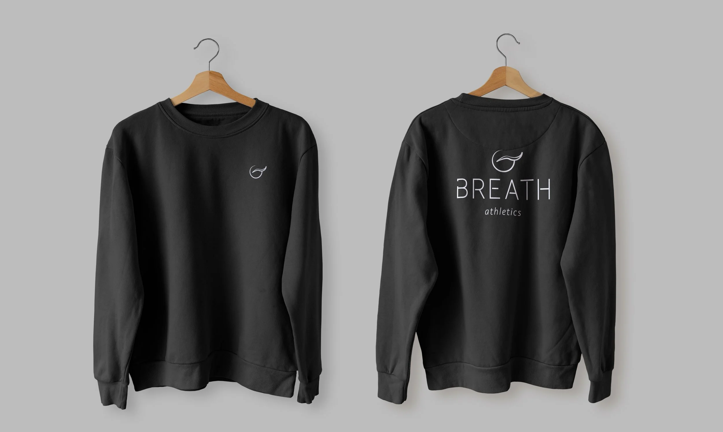Left: Black sweatshirt with white logo mark (circle & swish) on chest. Right: Black sweatshirt with white logo centered on back