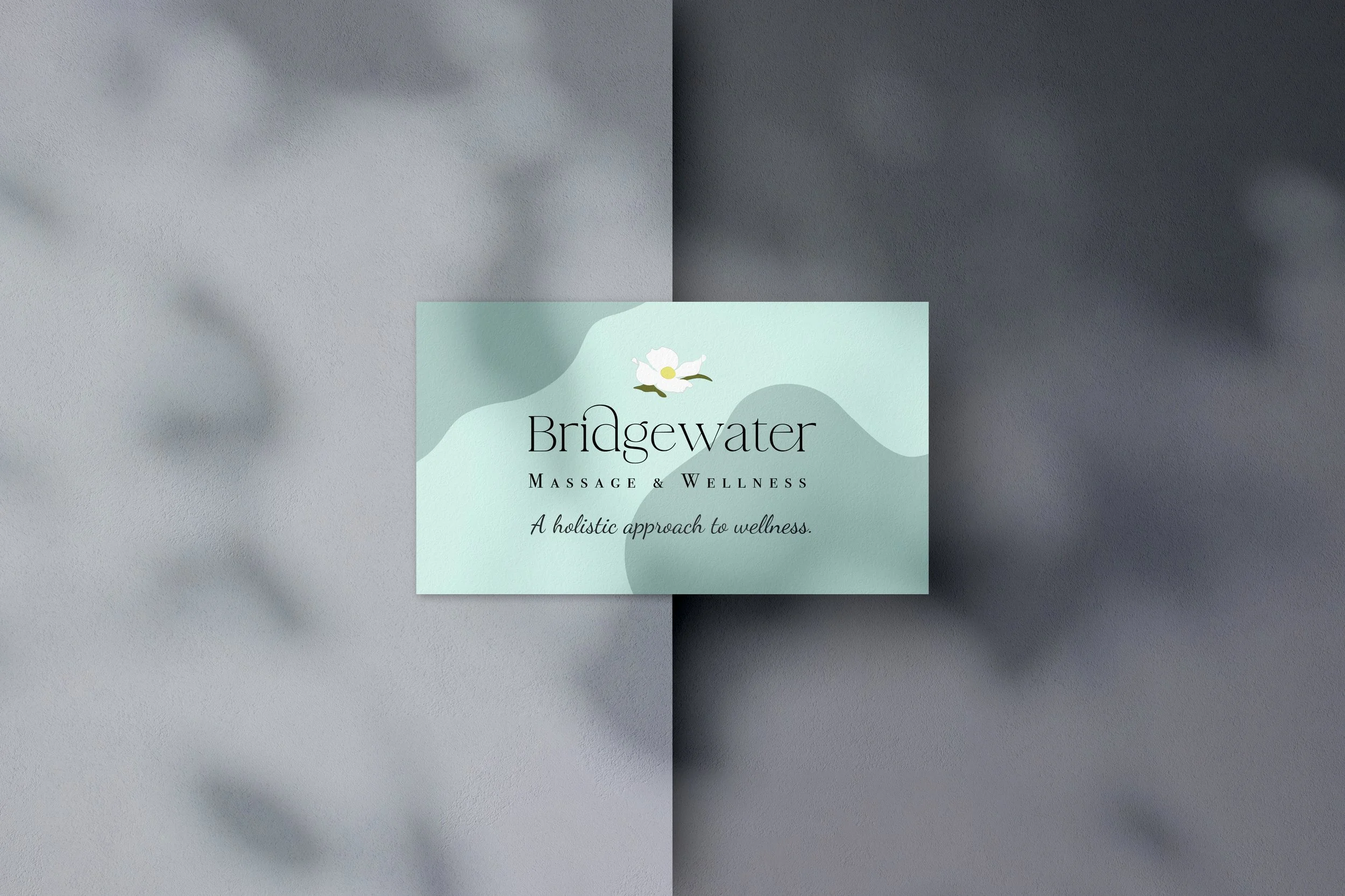 Business card shows full color logo shown on light blue and dark blue background. Business card is over a two toned gray background.