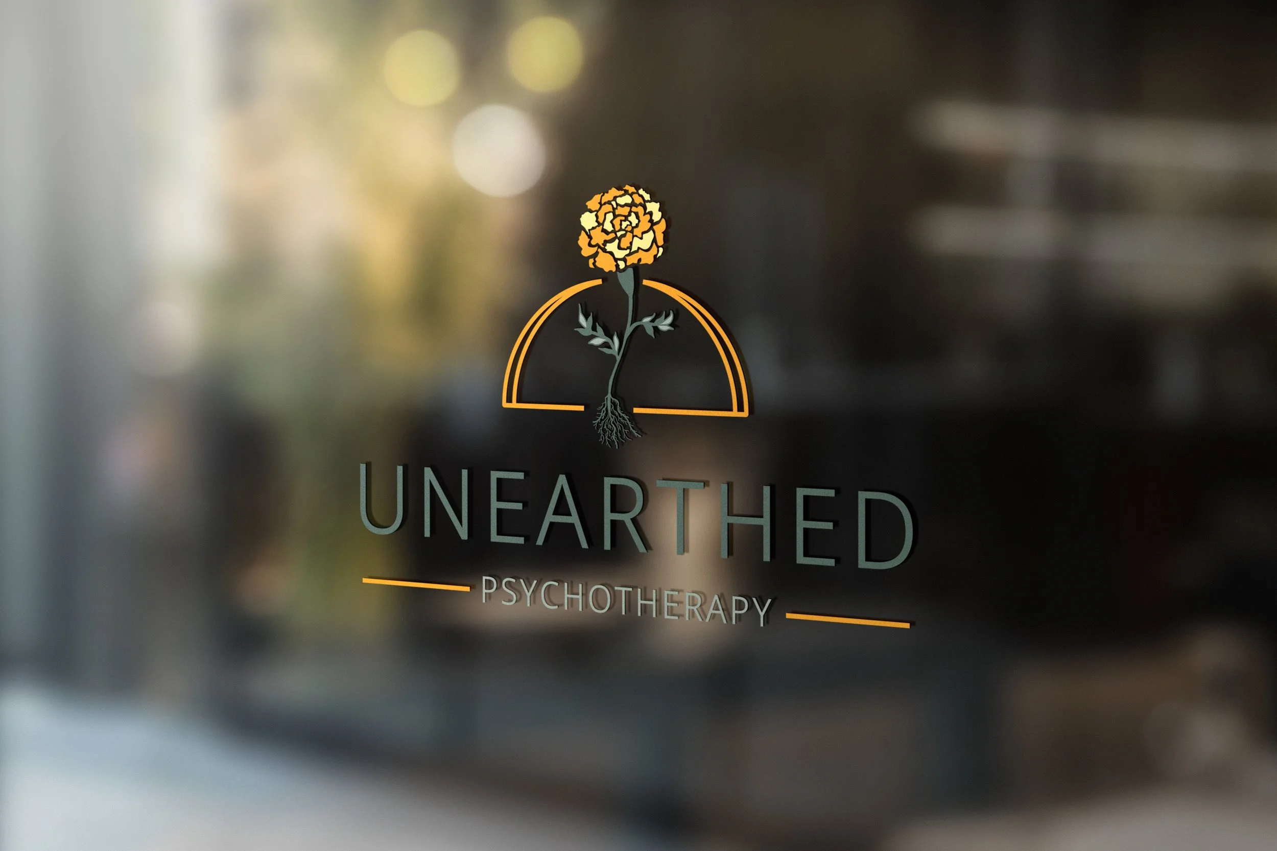 Unearthed Psychotherapy's logo is mocked up as a full color vinyl sticker on glass that reflects a blurry street scene.