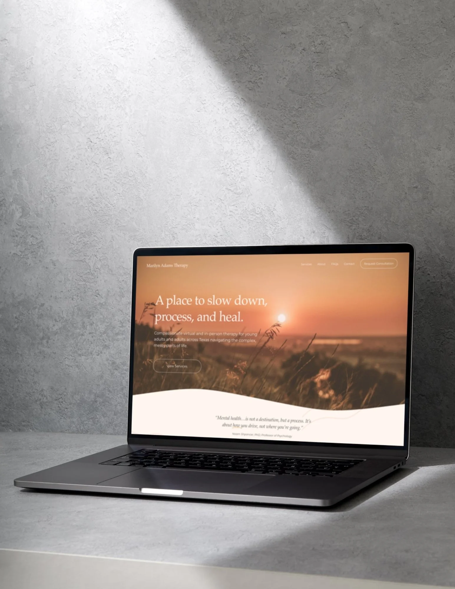 An opened laptop rests on a counter with an orange themed website on the screen.