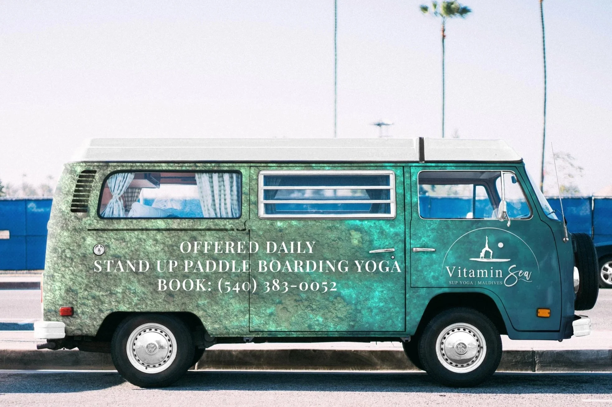Van wrap showing ocean with aquatic vegetation, white logo over door, and yoga info on left reading "OFFERED DAILY. STANDUP PADDLE BOARDING YOGA. BOOK + phone number. Van is on coastal street with palm trees behind.