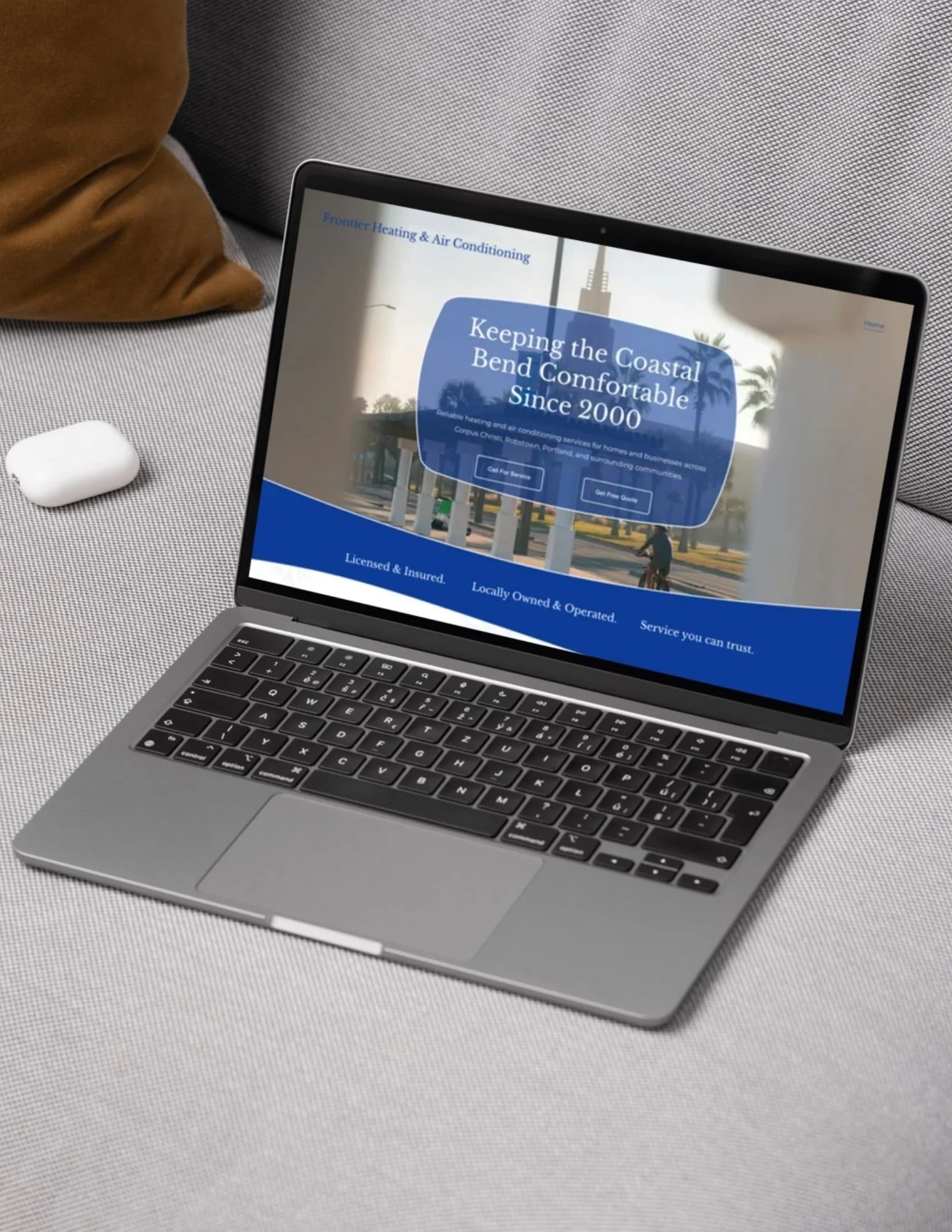 An opened laptop rests on a couch with a blue themed website on the screen.