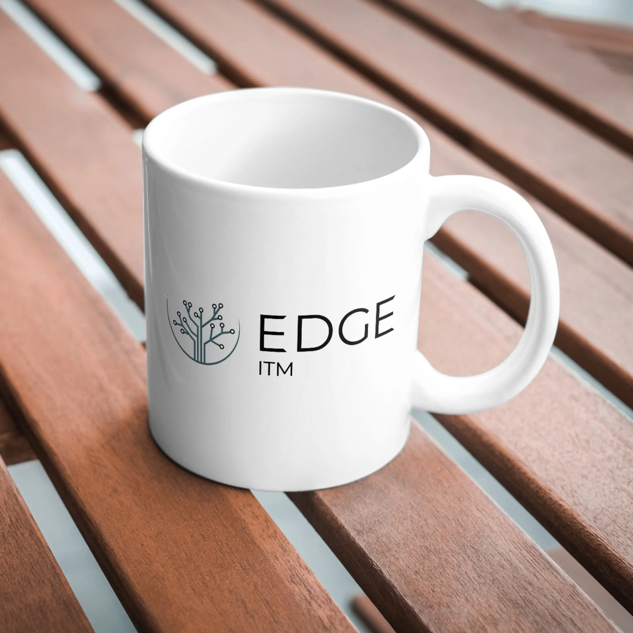 Blue and black logo design mocked up on white coffee mug, placed on a wood-slat table