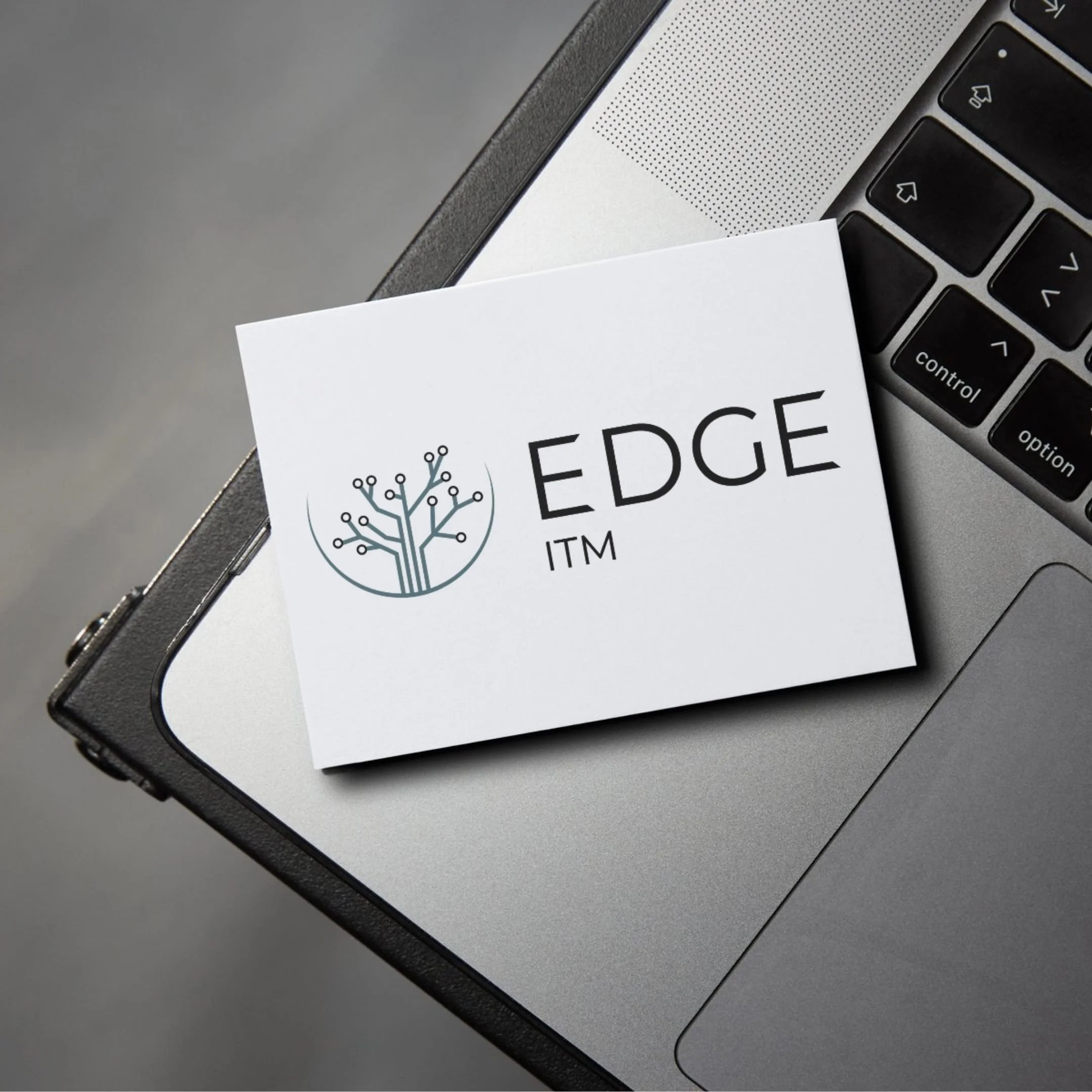 White business card with blue and black logo, placed on edge of a laptop keyboard.