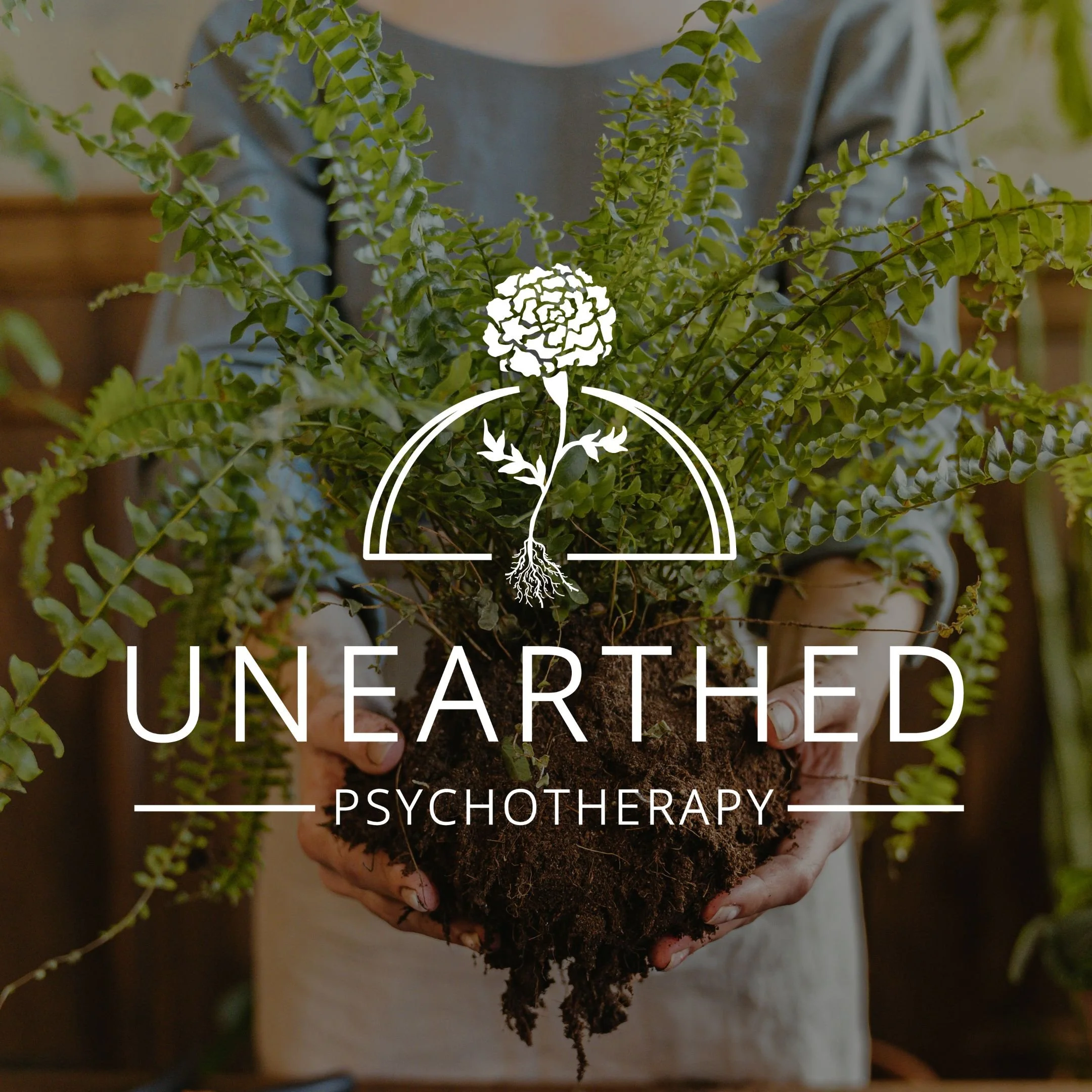 Image Alt Text: White Unearthed Psychotherapy logo is placed over an image of person holding an unpotted fern with exposed dirt and roots. Logo: Marigold with exposed roots is placed over a semi circle. Marigold design is placed above "UNEARTHED," wh