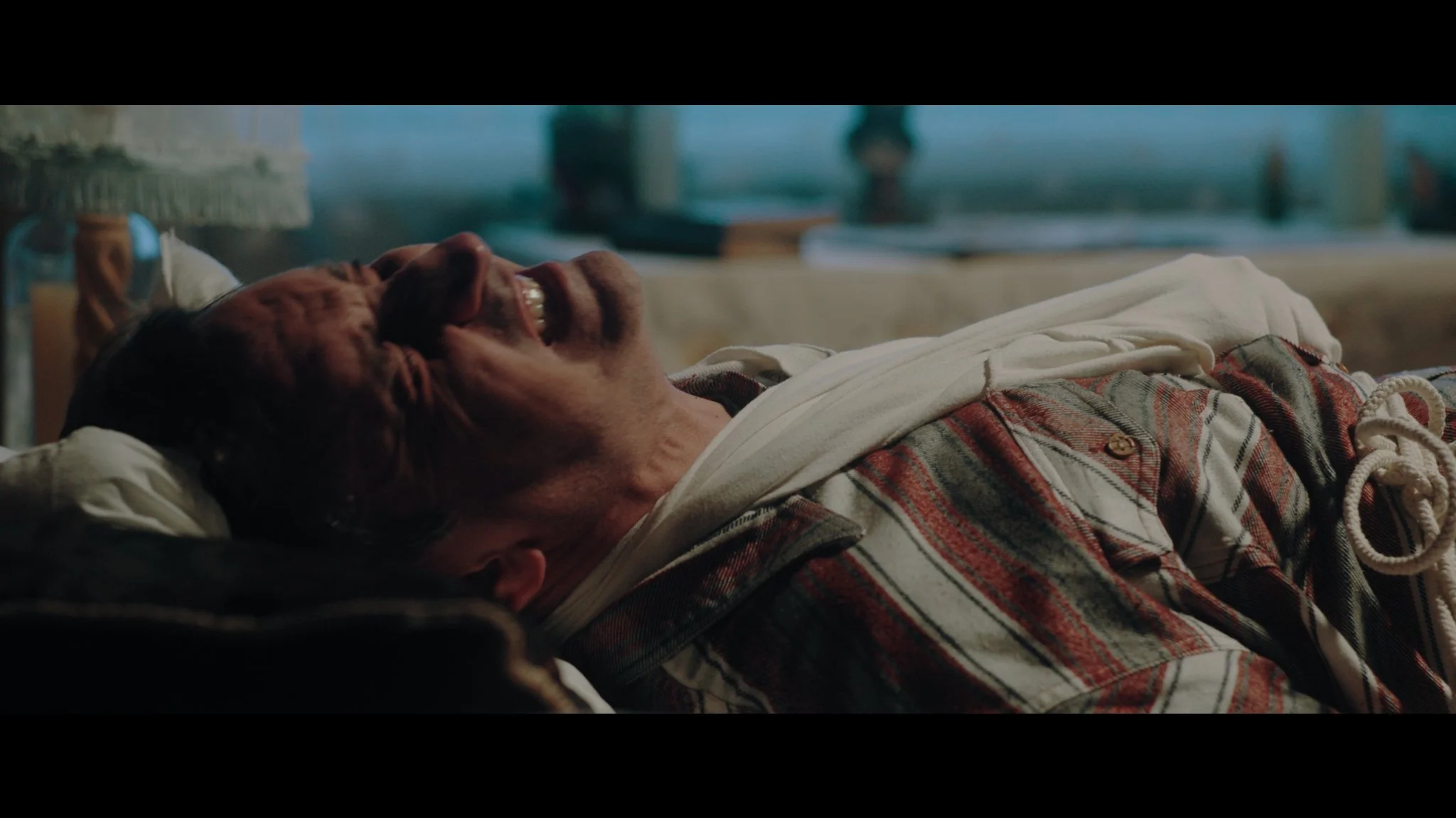Hombre acostado en la cama sonriendo, con expresión de felicidad, en un fondo doméstico