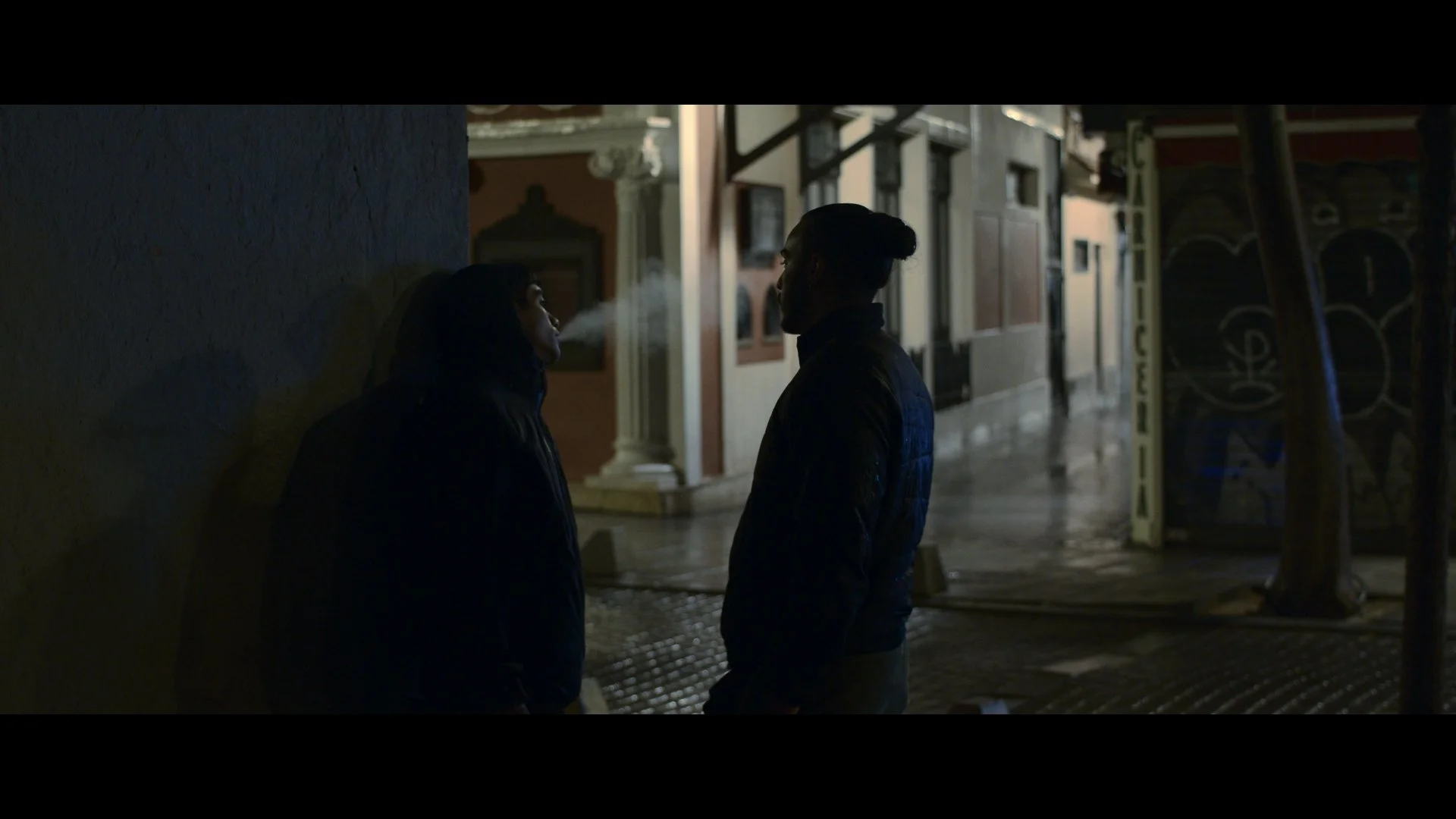 Dos personas en la calle en la noche, una de ellas exhala vapor.