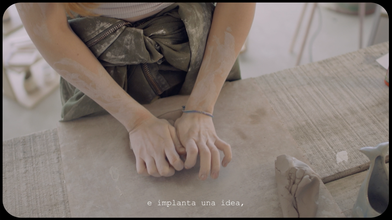 Una persona modelando arcilla en una mesa de madera, con las manos en posición de trabajar la arcilla.