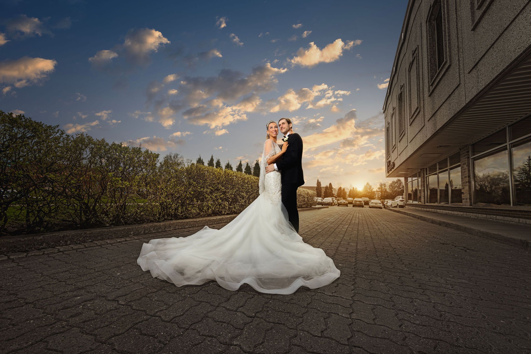 Romantic sunset wedding portrait in Montreal: a bride and groom embrace, framed by a glowing sky and sweeping gown.