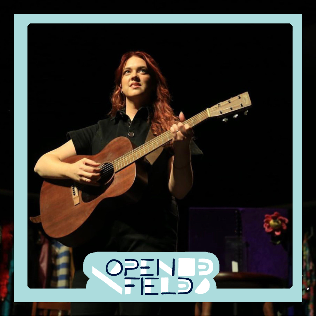 Person playing an acoustic guitar on stage with "Open Field" logo overlay.