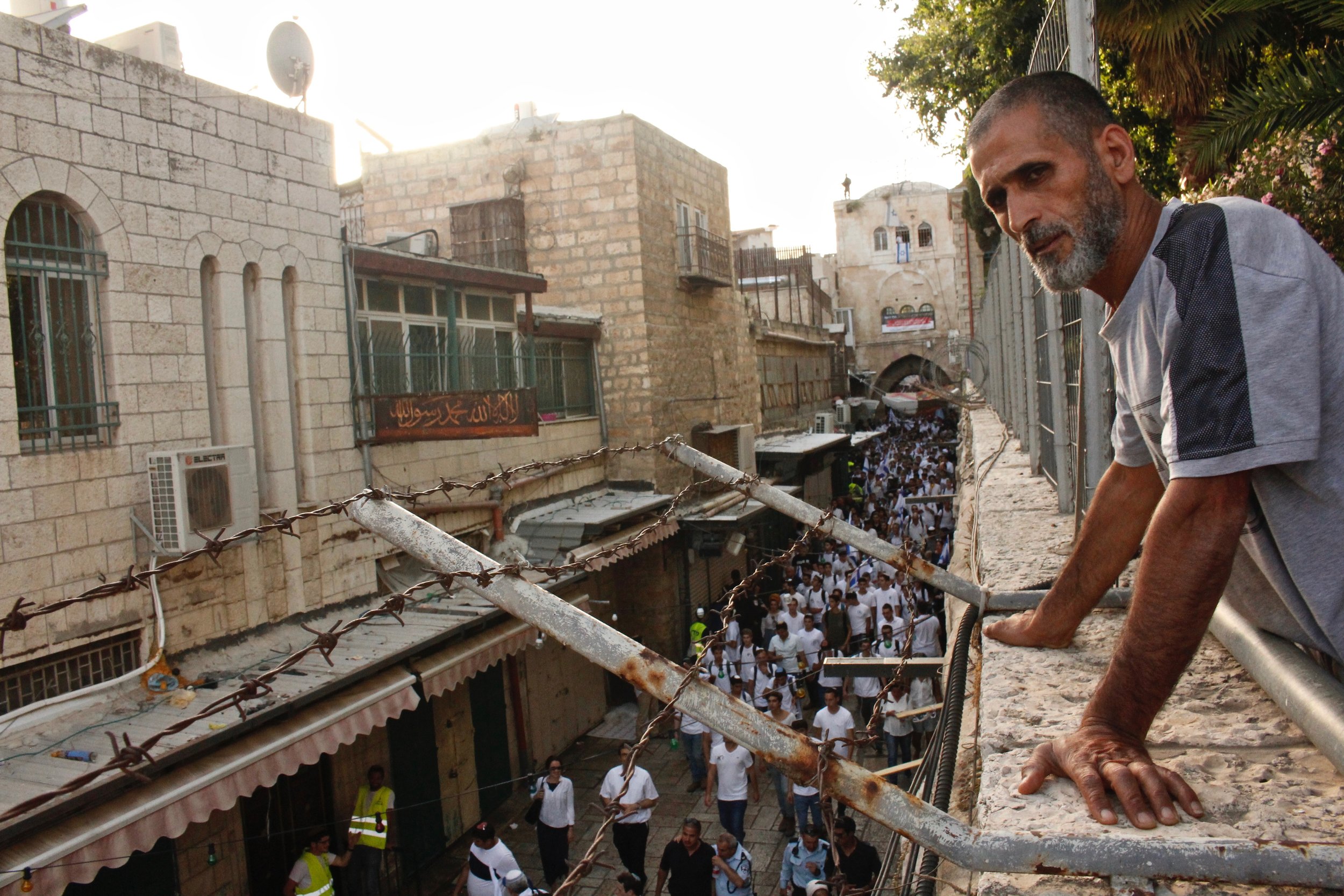 An Arab Palestinian resident of Jerusalem's Old City watches Jewish Israelis celebrate the annual "Jerusalem Day" holiday, in which the country marks its victory over the Jordanians in the 1967 Six Day War. June 2019.