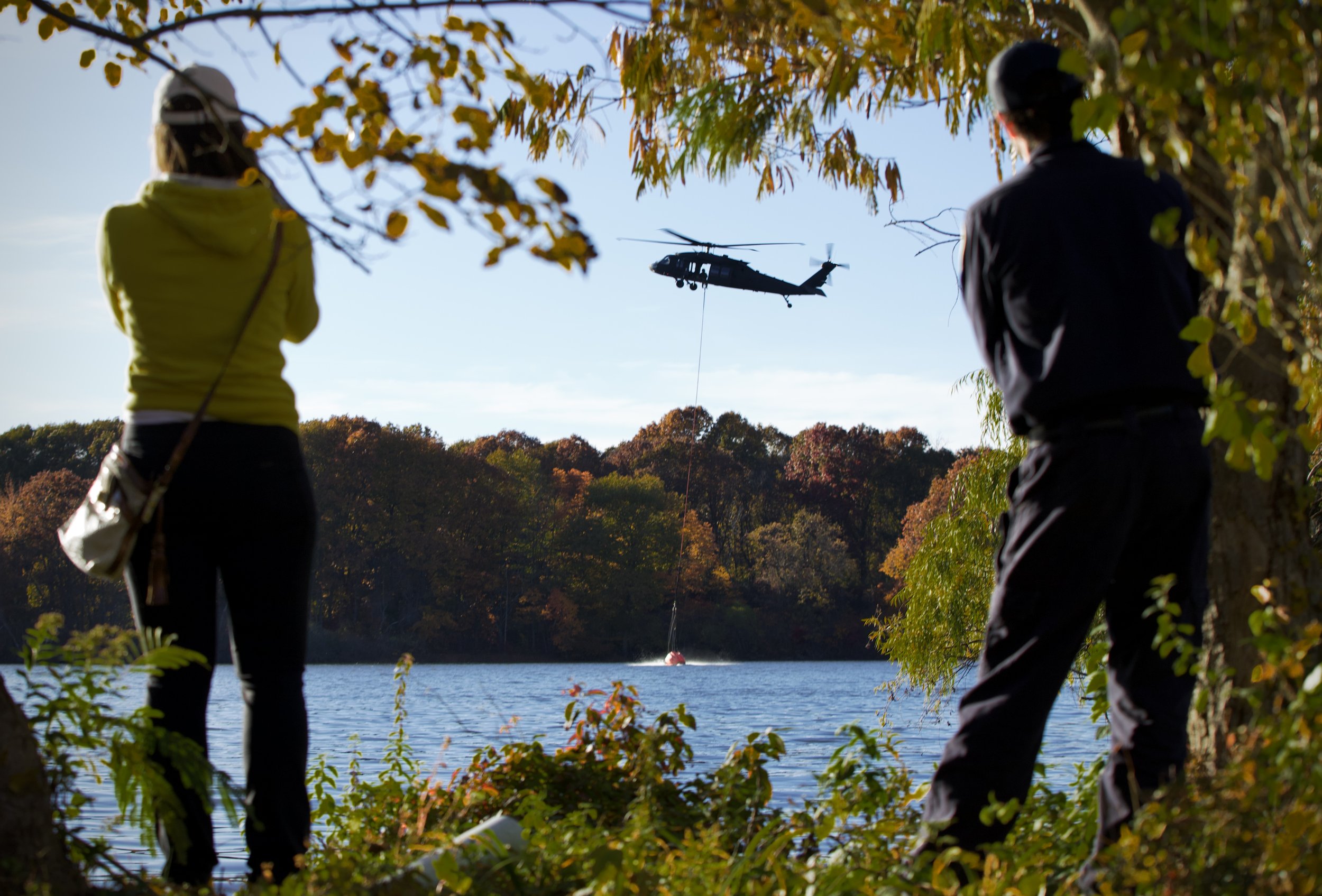 Oct. 25, 2024 — Local residents watch helicopters of the Connecticut National Guard as they collect lake water to extinguish a large brush fire in Berlin, CT.