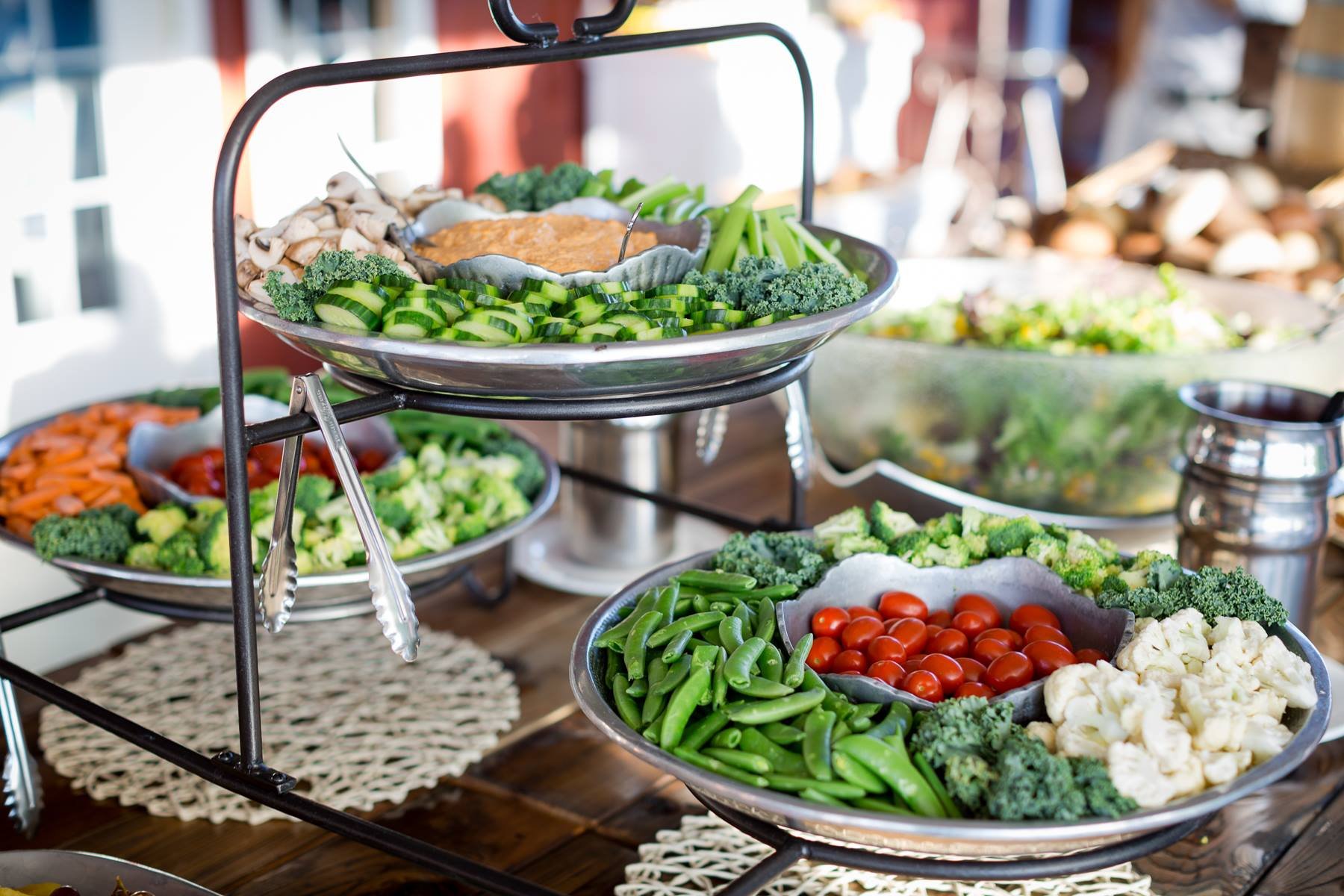 Colorful vegetable platter with sliced cucumbers, mushrooms, carrots, cherry tomatoes, snap peas, broccoli, cauliflower, and dip.