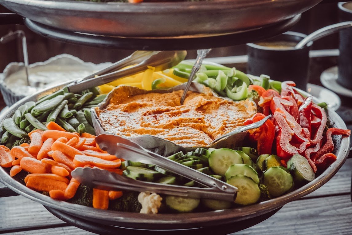 Colorful vegetable platter with carrots, bell peppers, cucumbers, and dip.